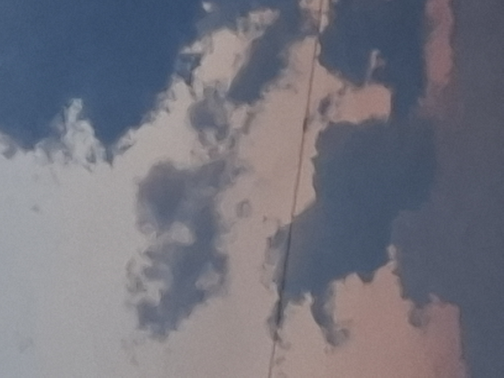 The image is a close-up, low-angle shot of a cloudy sky, likely taken at dusk due to the pinkish and purplish hues mixed with the blues and grays of the clouds. A thin, dark horizontal line, possibly a wire or cable, stretches across the middle of the frame, suggesting the presence of infrastructure. The clouds are varied in texture and density, with some appearing wispy and light, while others are dark and ominous. No people, specific landmarks, or identifiable structures within the city of Kirchardt, Germany, are visible. The focus is entirely on the atmospheric conditions of the sky.