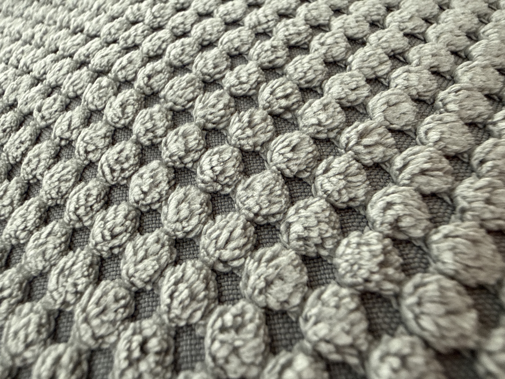 The image shows a close-up of a textured gray surface. The surface is composed of numerous small, tightly packed, raised, textured "bumps" or "knots." The arrangement is organized, with the bumps aligned in rows and columns. The overall impression is one of regularity and repetition. The image does not provide information about location, people, subjects, objects, actions, interactions, or the environment beyond the textured surface itself. Thus, there is no information to suggest it is located in the city of Lovech, Bulgaria.