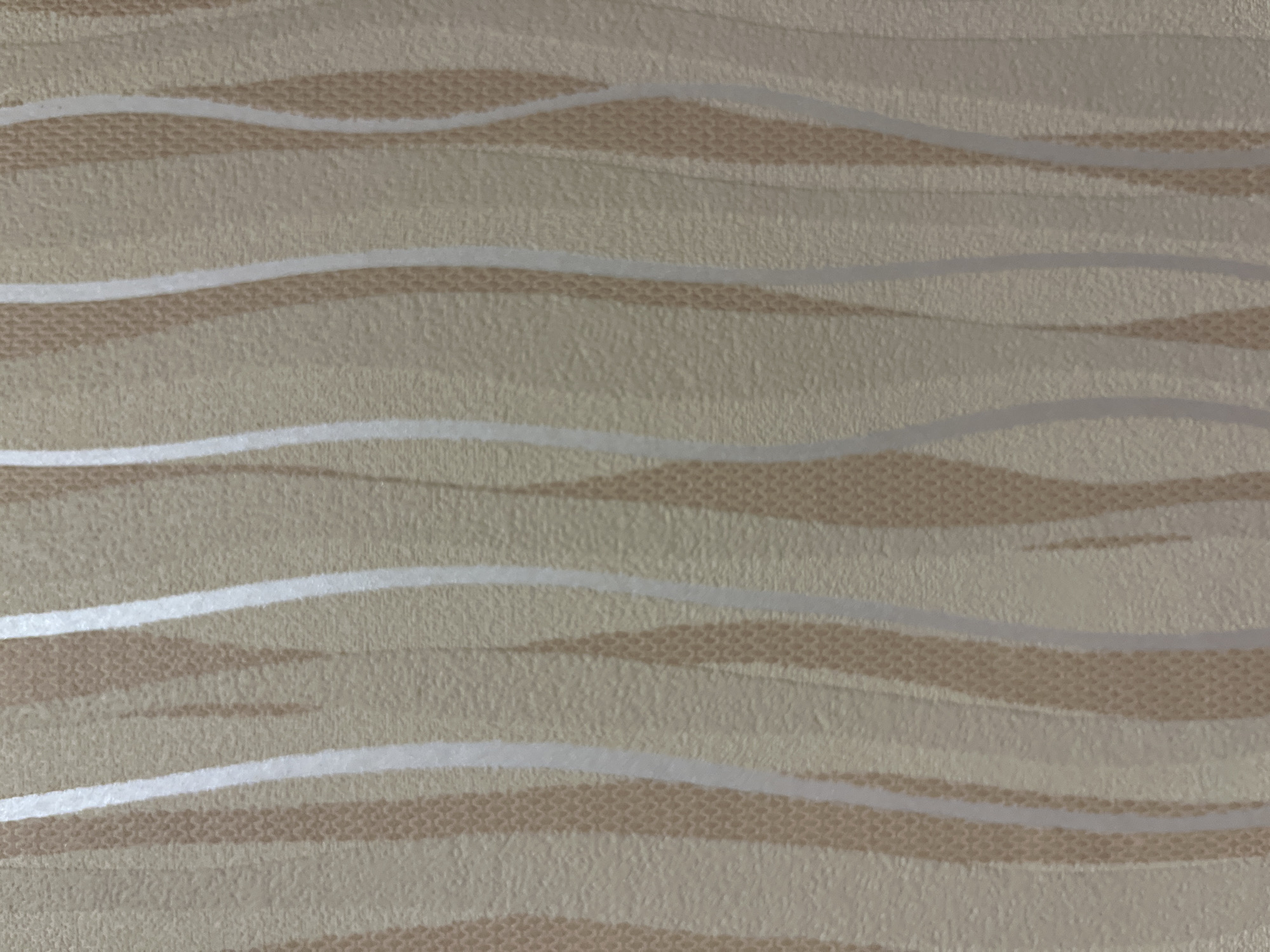 This is a close-up, full-frame, eye-level, static shot of textured wallpaper. The wallpaper has a pattern of vertical, wavy stripes in shades of beige and cream. Some stripes have a subtle, fine, raised texture, possibly resembling a woven or embossed material. The overall impression is one of subtle, neutral tones and a soft, tactile finish. There are no people, objects, or discernible environmental features visible beyond the wallpaper itself, which fills the entire frame. The image does not provide any information about its location in Moscow, Russia, or any other specific context.