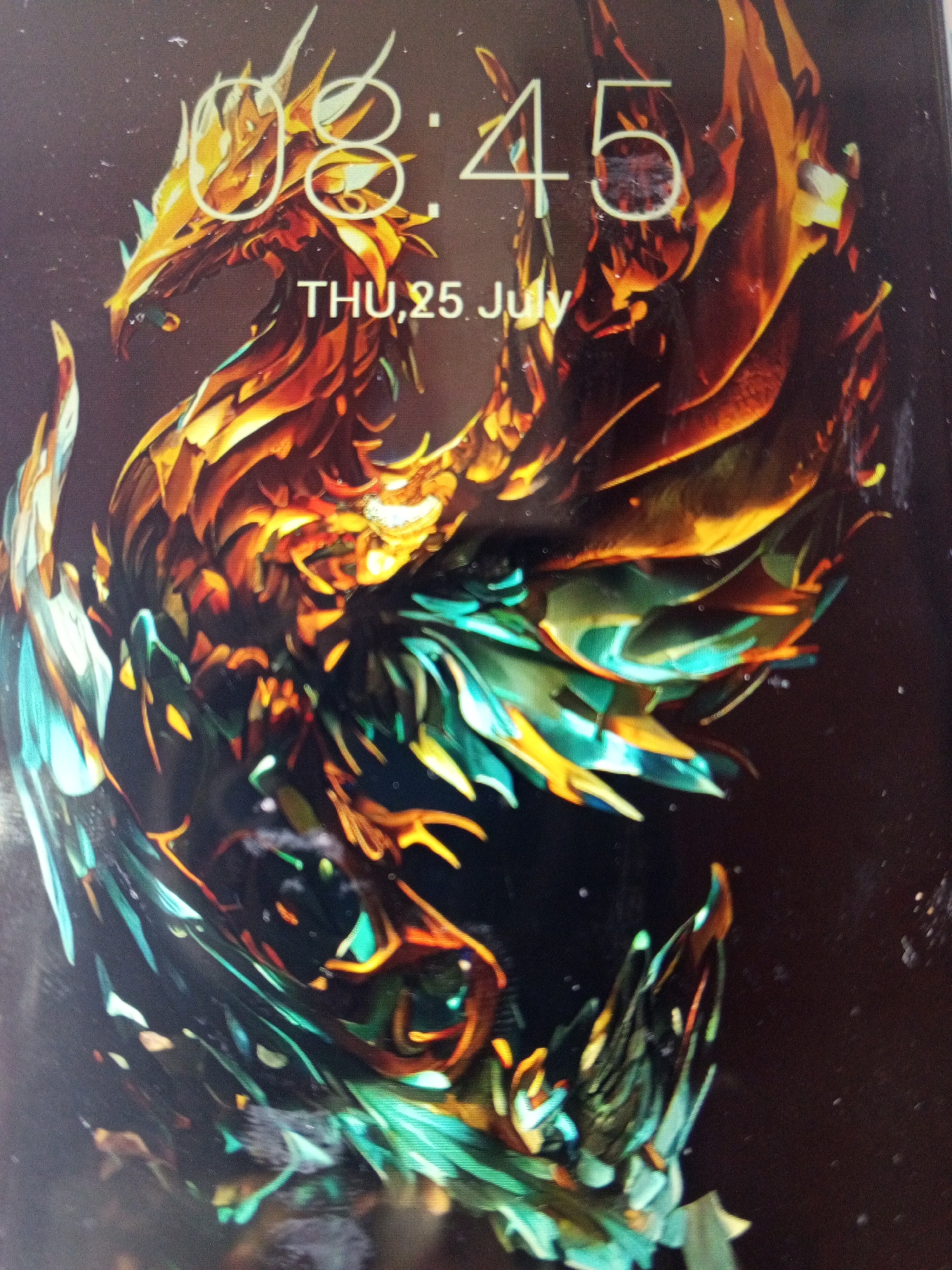 The image is a close-up of a mobile phone screen displaying a lock screen. The lock screen wallpaper features an abstract, stylized depiction of a phoenix or dragon-like creature. The creature is rendered in a vibrant color palette of golds, oranges, reds, and turquoise. The image also displays the time "08:45" and the date "THU, 25 July". There is no indication of the location being Tinaquillo, Venezuela.