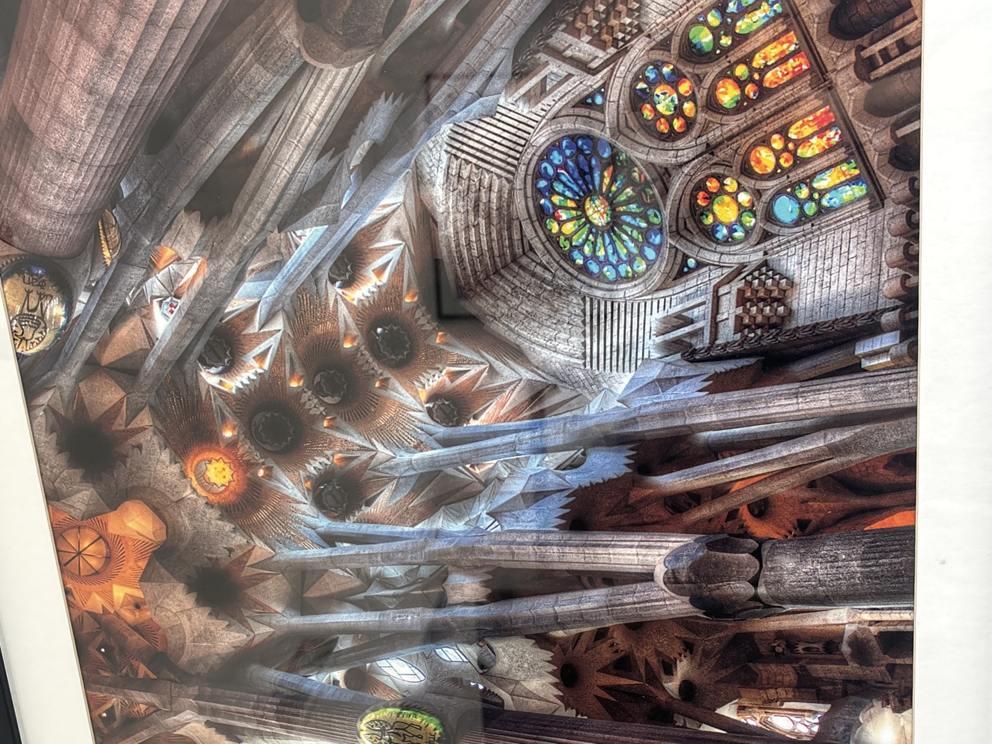 This image depicts the interior of a grand, architecturally complex structure, characterized by soaring, tree-like columns that branch out to support an intricately designed ceiling. The ceiling features a starburst pattern with glowing circular elements, suggesting a sophisticated lighting system or natural light filtering through openings. The architecture exhibits a blend of organic and geometric forms, with a rough, stone-like texture dominating the surfaces. Prominently featured are several large, circular stained-glass windows, bursting with vibrant colors of blue, green, yellow, and red, casting colorful patterns onto the surrounding stone. The scene is bathed in warm, artificial light, enhancing the rich textures and colors of the architecture and stained glass. The overall impression is one of awe-inspiring scale and detailed craftsmanship.
The image does not depict Dubai, United Arab Emirates. This architectural style is characteristic of Antoni Gaudí's work, most notably the Sagrada Familia in Barcelona, Spain. There are no people, actions, or interactions visible in the image.