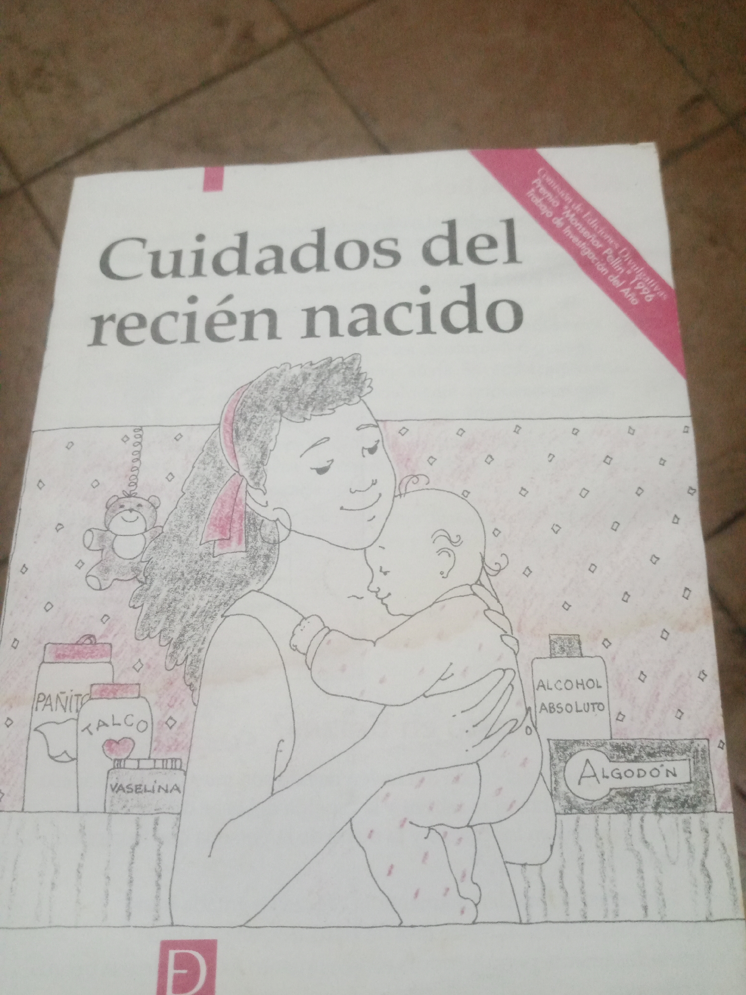The image shows the cover of a book titled "Cuidados del recién nacido," which translates to "Newborn Care." The cover features a hand-drawn illustration of a woman holding a baby. Several baby care products are depicted in the foreground, including containers labeled "PANIT," "TALCO," "VASELINA," "ALCOHOL ABSOLUTO," and "ALGODÓN." A small teddy bear is hanging from the woman's hair. In the upper right corner of the cover, text in a pink ribbon indicates "Comisión de Ediciones Desiguales," "Premio 'Monseñor Pellín' 1976," and "Trabajo de Investigación del Año." The book cover is placed on a surface that appears to be a tiled floor. The image does not contain any information or visual cues that would allow for the identification of a specific location within the city of Santa Ana, Venezuela, or any other city.