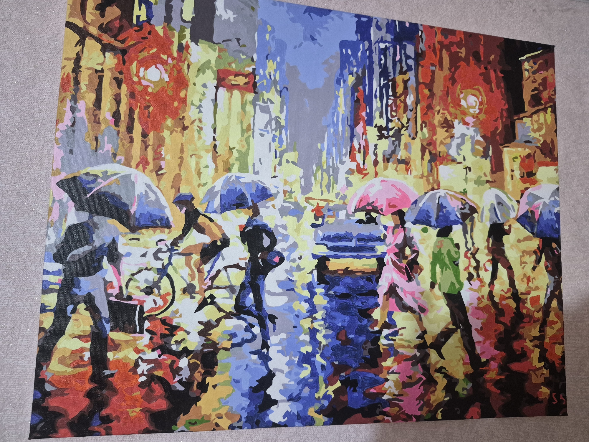 This vibrant painting depicts a bustling city street scene during a rain shower, likely at night. The artwork employs a distinct, blocky color-field style, giving it an almost mosaic-like appearance.
The primary subjects are several stylized figures moving through the rain. Most are pedestrians holding open umbrellas of varying colors, including shades of grey, blue, and a prominent pink. One figure is seen riding a bicycle, also under an umbrella. The figures are rendered with strong, contrasting colors, emphasizing their shapes against the luminous background.
The setting is an urban environment, characterized by tall, abstract buildings in the background that are brightly lit with artificial lights. These lights cast vivid hues of yellow, orange, and red, intermingled with cooler blues and greys. The wet street surface reflects these brilliant lights and the forms of the people and umbrellas, creating a shimmering, dynamic foreground and adding to the overall visual texture.
The activity portrayed is people navigating a city street in the rain, suggesting movement and the everyday rhythm of urban life. The time of day is clearly evening or night due to the reliance on artificial illumination. The weather is definitively rainy, a fact underscored by the umbrellas and the reflective puddles. The painting evokes a sense of urban energy and the unique beauty of city lights on a wet night. The artist's initials, "SS," are visible in the bottom right corner.