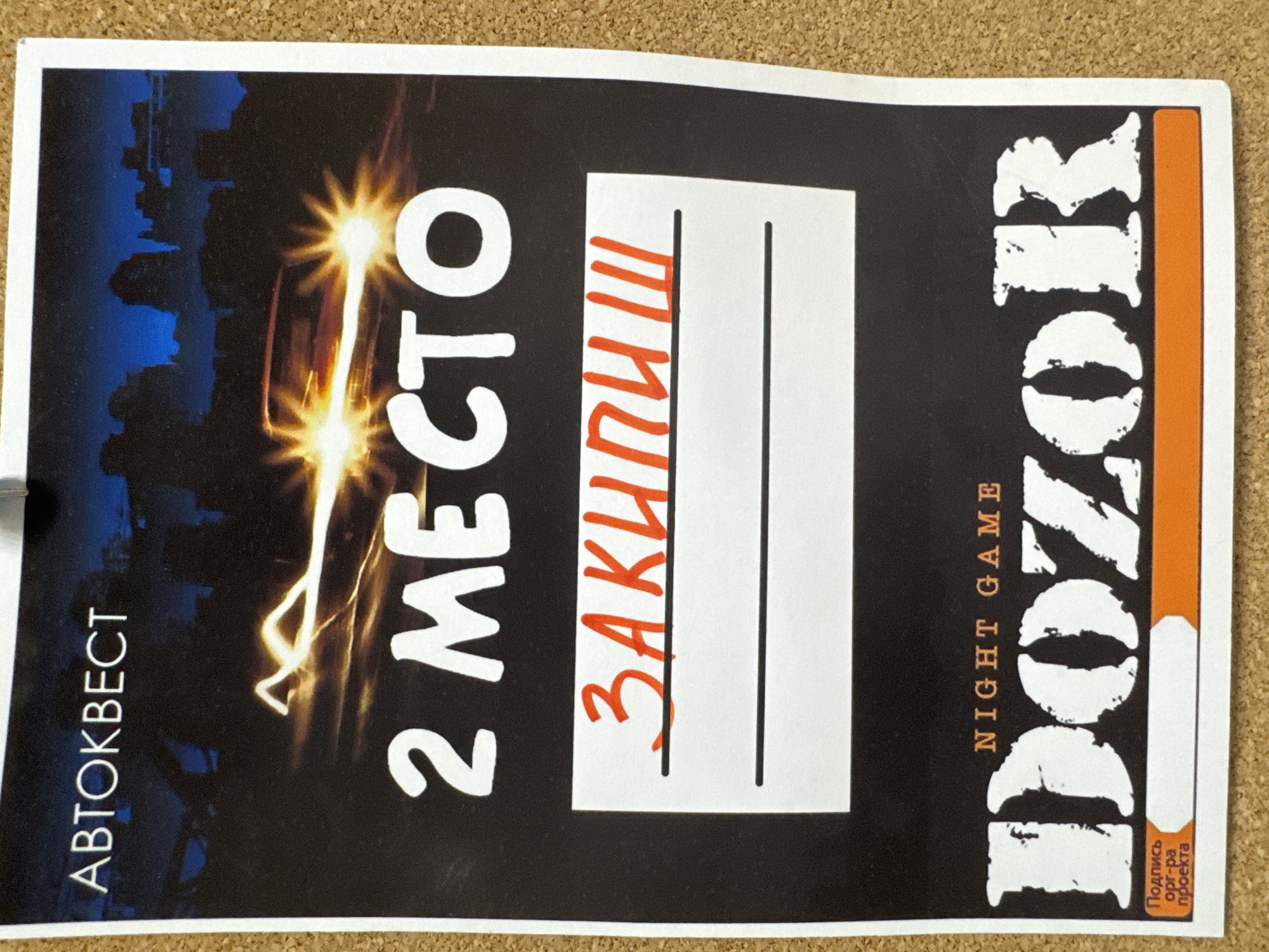 This image displays a certificate or award, likely from a real-life game event, placed on a light brown, textured surface resembling a cork board. The certificate itself is rectangular with a black background, framed by a white border, and features white and orange text along with graphics.
The main subject is the certificate, which signifies an achievement. On the left side, vertically oriented in white, is the text "АВТОКВЕСТ" (AVTOKVEST), indicating a car-based quest game. The central prominent text, also in white, reads "2 МЕСТО" (2 MESTO), meaning "2nd PLACE." To the right of this, within a white box, is handwritten red text that appears to be "ЗАКИНУШ" (ZAKINUSH), possibly a team or participant's name.
On the far right, large, distressed white letters form the word "DOZOR" (DOZOR), a well-known night game franchise, with "NIGHT GAME" written beneath it in smaller white text. In the bottom right corner, vertically oriented in orange, is "ПОДПИСЬ орг-ра проекта" (PODPIS ORG-RA PROEKTA), which translates to "Signature of project organizer."
The background graphic depicts a dark cityscape silhouette against a dark blue sky, illuminated by bright, star-like bursts of light and energetic streaks, emphasizing the "night game" theme. The certificate suggests the culmination of a competitive, adventurous urban game in Chaikovsky, Russia, where a participant or team secured second place.