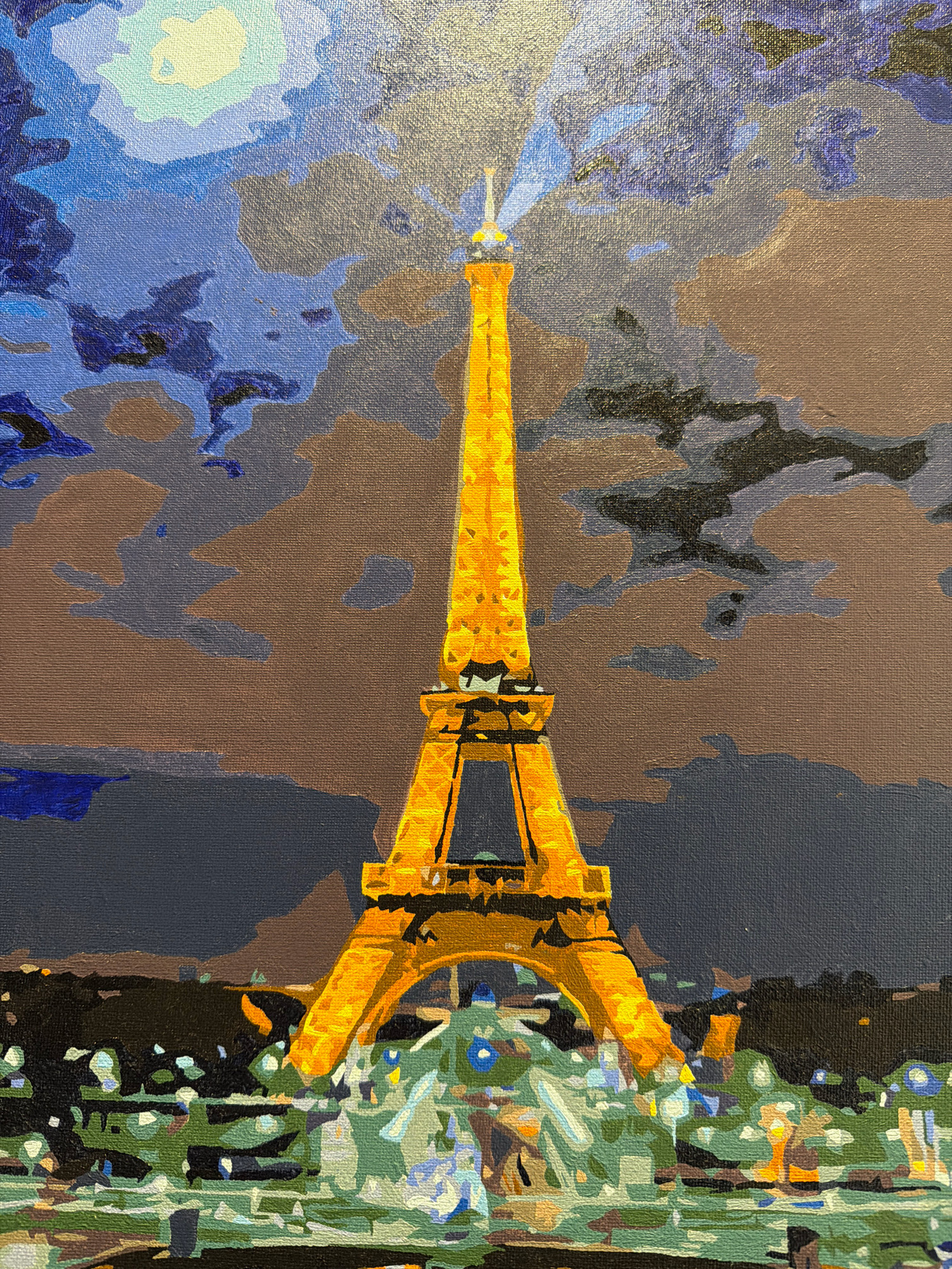 The painting depicts the Eiffel Tower at night, illuminated and casting a beam of light into the sky. The sky is a dramatic blend of blues and grays, with hints of yellow suggesting moonlight or artificial light. In the foreground, there is a suggestion of city lights or a park, rendered in a mosaic of greens, whites, and blues. The painting is done in a style that emphasizes blocks of color rather than fine detail. There is no indication that this scene is located in Kazan, Russia.