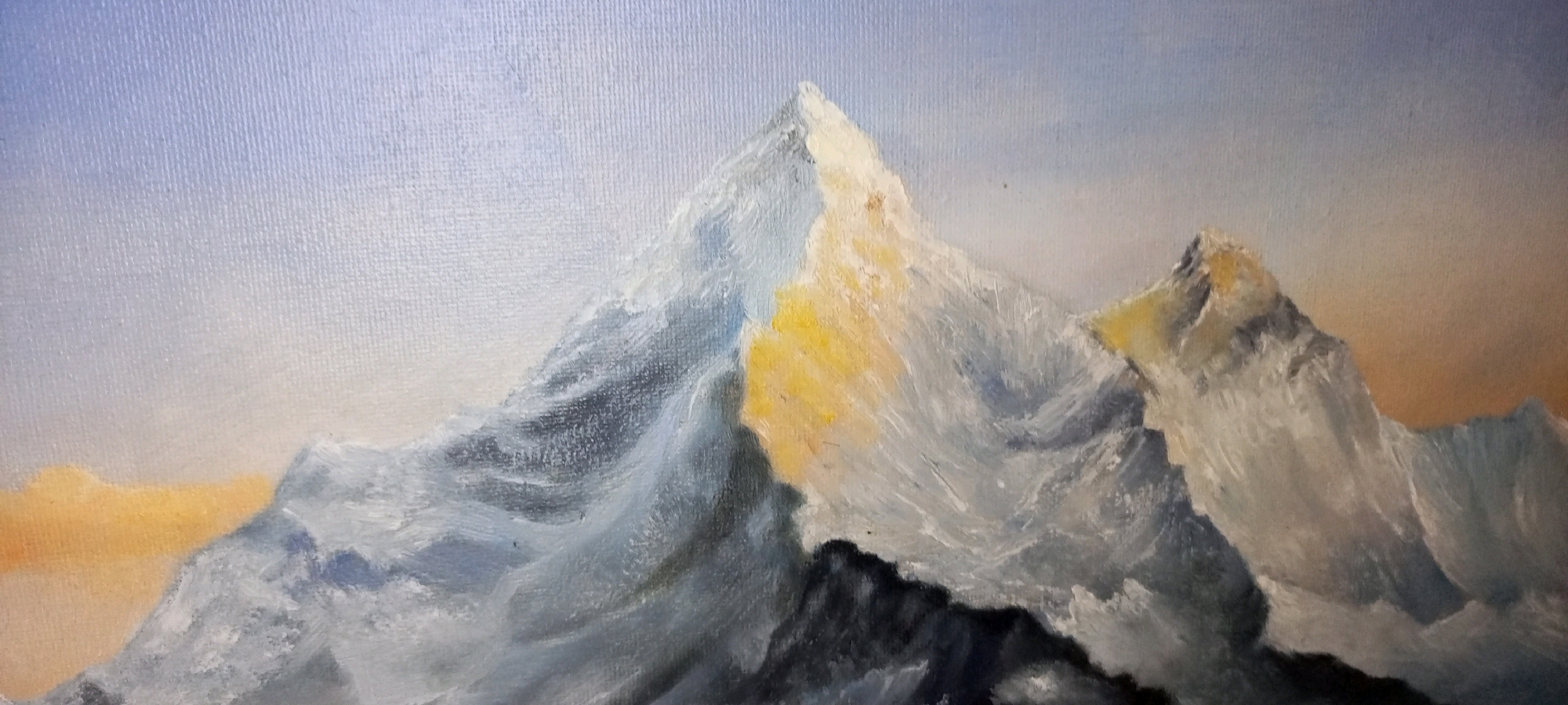 A painting depicts a mountainous landscape. The foreground features dark, craggy peaks, with lighter grey and white snow-covered mountains rising behind them. The largest peak is illuminated by a warm yellow light on its right side, contrasting with the cool blue and grey tones of its snow and rock. The sky transitions from a pale blue at the top to a soft orange and yellow near the horizon. The texture of the canvas is visible throughout the painting, indicating it is likely an oil painting. The scene is serene and majestic, evoking a sense of vastness and natural beauty. There are no people, objects, or actions indicated in the scene, and no specific location in Toru, Pakistan is identifiable.