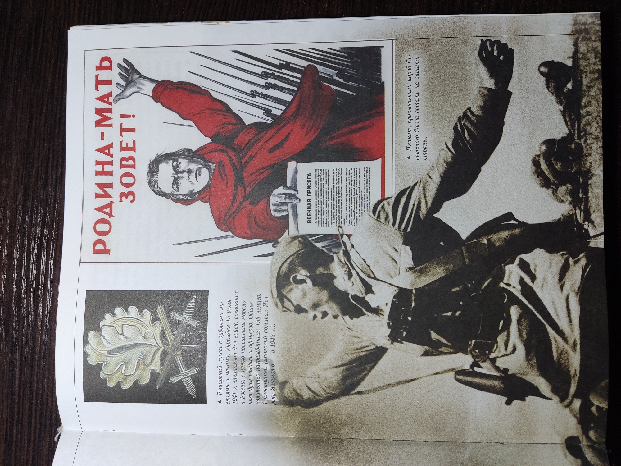 The image is of a page in a book showing two images; one is a propaganda poster, and one is of a soldier in action. The poster depicts a person in a red robe with an arm outstretched, and bayonets in the background. The words "РОДИНА-МАТЬ ЗОВЕТ!" (Motherland Calls!) are written in red. Underneath the poster is the text of a military oath. To the right of the poster is an image of a soldier seemingly in action, with his arm raised. To the left of the poster is an image of an Iron Cross. The image is likely from a book describing propaganda and military awards of the Soviet Union during WWII.