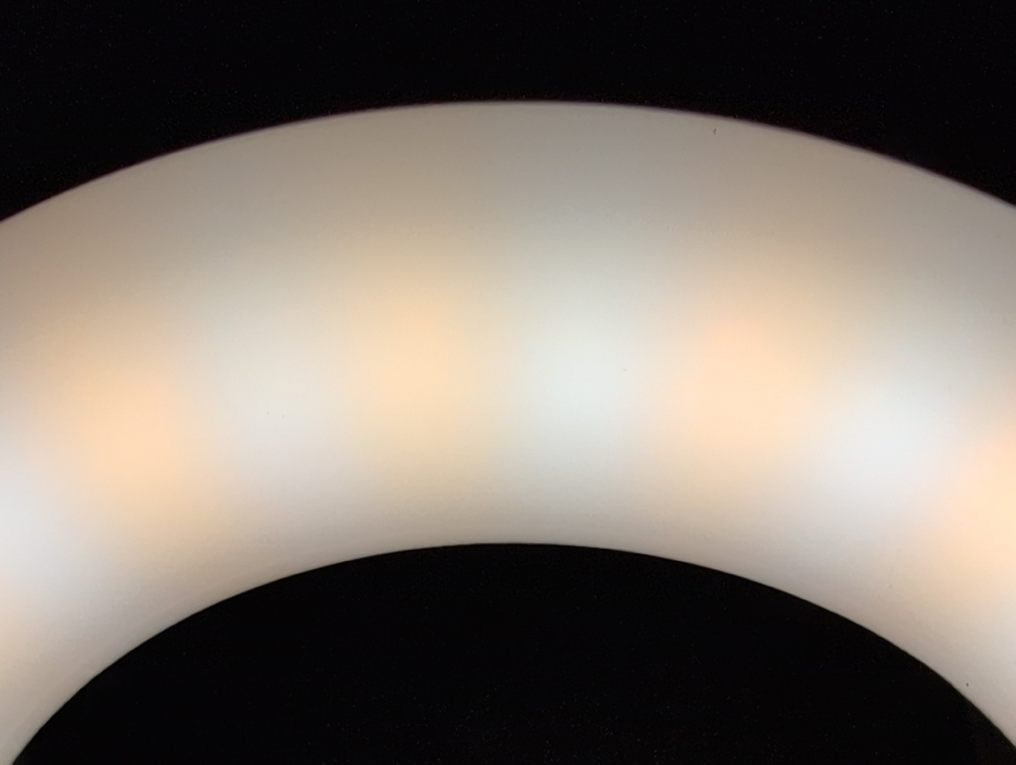 The image shows a close-up, abstract view of a curved, translucent object against a black background. The object appears to be illuminated from within or behind, with soft, warm light creating a gradient of color from white to a peachy orange. The texture of the object is smooth and matte. The image does not contain any discernable elements that would allow for identification of a specific location in Louisville, United States of America.