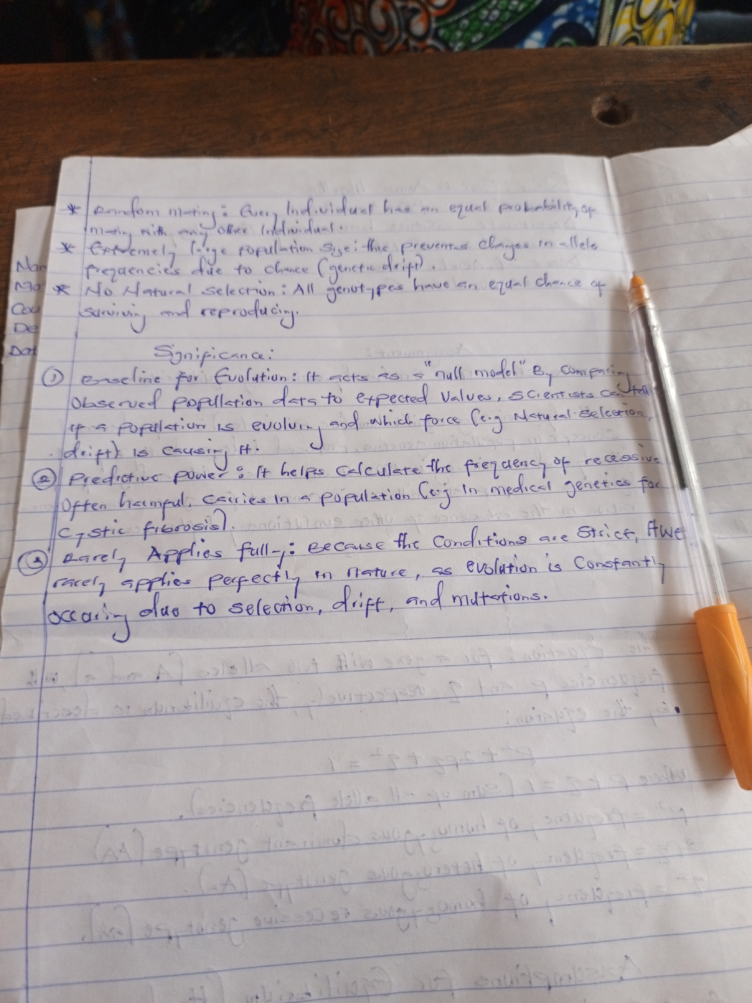 The image captures a close-up, top-down view of a handwritten notebook page resting on a wooden surface. The primary focus is a white, lined paper filled with academic notes written in blue ink, cursive script. An orange and clear plastic ballpoint pen is positioned diagonally across the right side of the page, partially covering some text.
The notes detail conditions for a concept in population genetics, likely Hardy-Weinberg equilibrium, including: "Random mating," "Extremely large population size," and "No Natural Selection." It specifies that these conditions ensure "Every Individual has equal probability of mating with any other Individual," that large populations "prevent changes in allele frequencies due to chance (genetic drift)," and that "All genotypes have an equal chance of surviving and reproducing."
Following these conditions, a section titled "Significance" explains:
1. It acts as a "baseline for Evolution" or "null model," allowing comparison of "observed population data to expected values" to determine if "a population is evolving and which force (e.g., Natural Selection, drift) is causing it."
2. It has "Predictive power," helping to "calculate the frequency of recessive carriers in a population (e.g., in medical genetics for Cystic fibrosis)."
3. It "Rarely Applies fully" in nature "because the conditions are strict," and "evolution is constantly occurring due to selection, drift, and mutations."
The background consists of a wooden table with visible grain and a small, dark circular mark. Beyond the table, a blurry, colorful fabric or mat with an abstract pattern is visible. The scene suggests an indoor study environment, likely during daylight hours, given the clear visibility of the text.