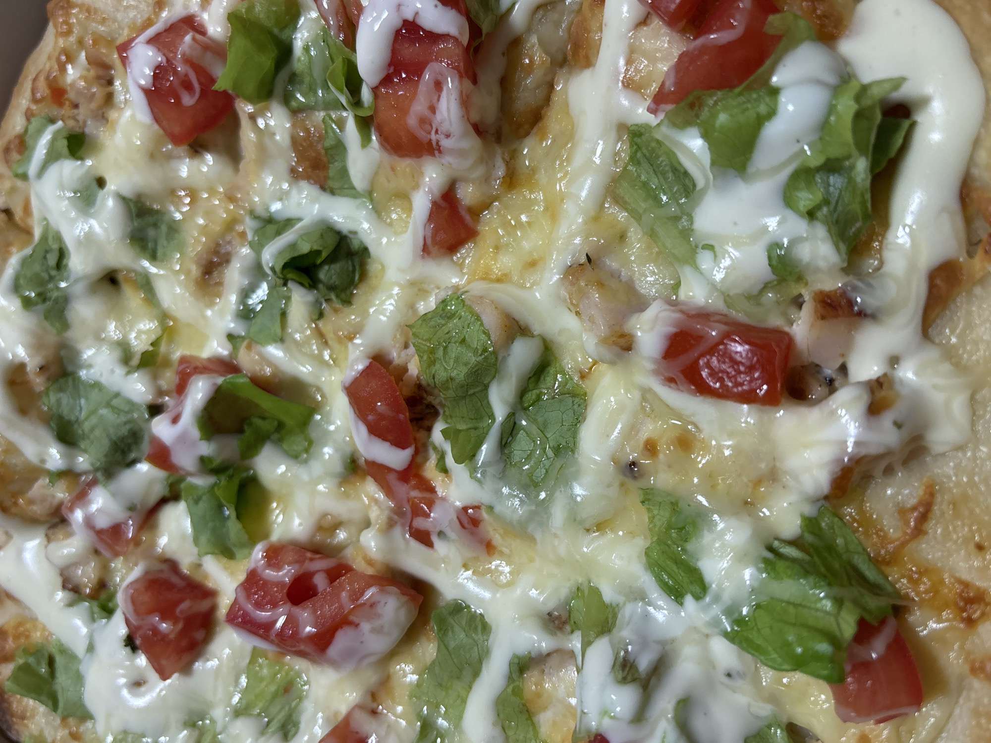 The image is a close-up shot of a pizza. The pizza appears to be topped with mozzarella cheese, lettuce, tomatoes, and white sauce. The location of the image is unknown, but the city of Perm, Russia, is mentioned in the prompt. Without additional contextual information, I cannot confirm the location.