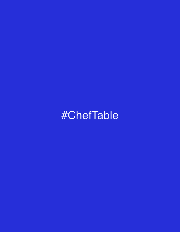 The image shows a solid blue background with the text "#ChefTable" in white, centrally located. The image does not contain sufficient information to determine the location, city or country. No people, subjects, objects, actions, interactions, or environment are visible in the image besides the text.