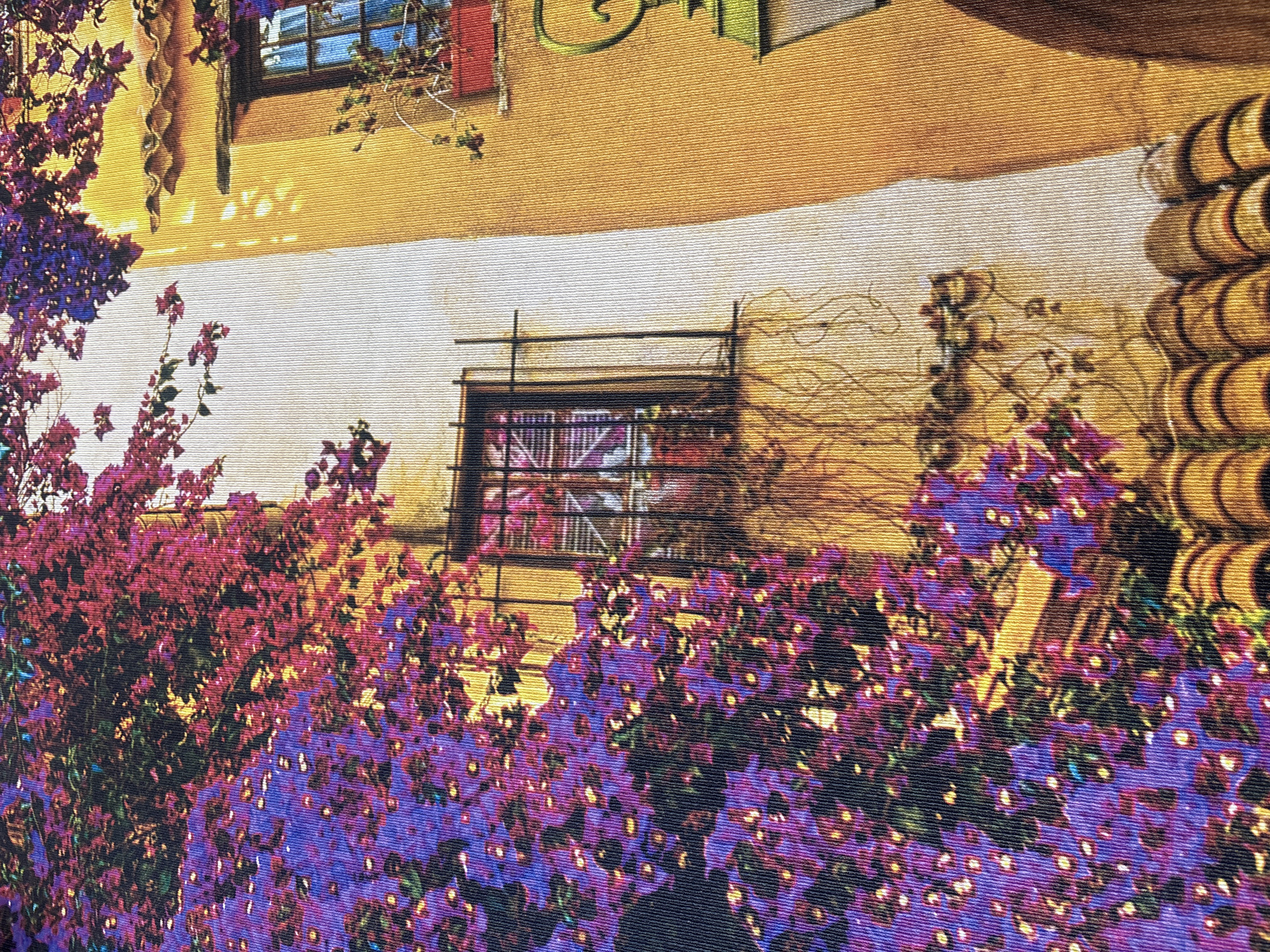 This is a photograph of a building with a wall of bougainvillea flowers in the foreground. The building has an orange-yellow facade with a tiled roof. There is a window with a black wrought-iron grate. A green lamp is visible on the right side of the image. The image is taken from a low angle, looking up at the building and flowers. The photograph appears to be of a building located in Georgiyevsk, Russia, in the city of Georgiyevsk.