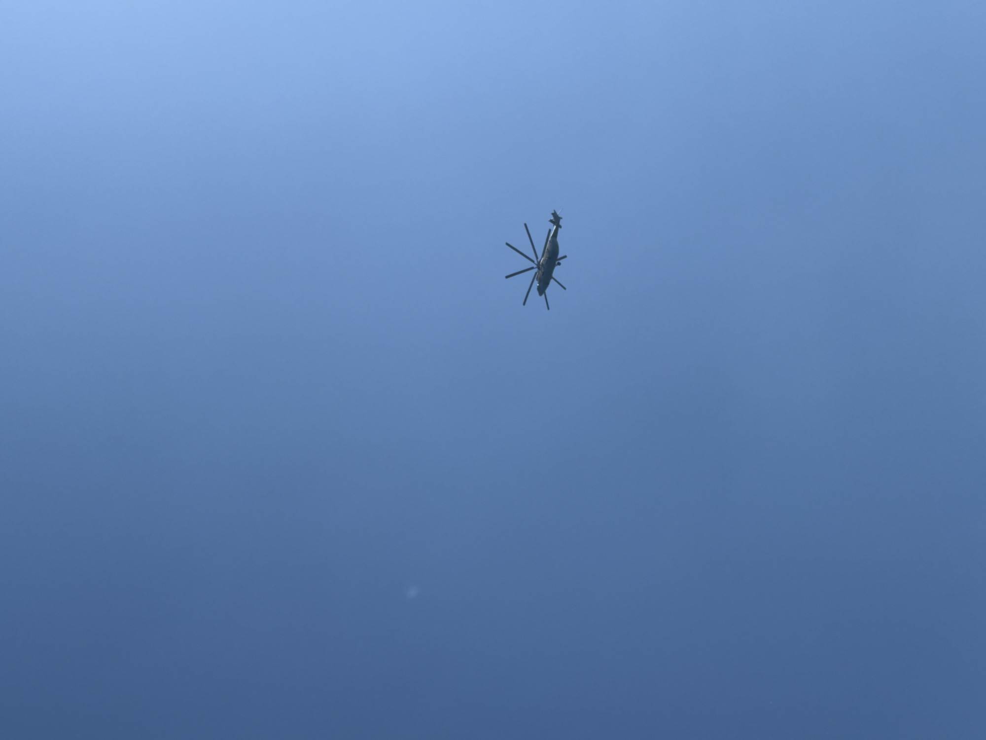 A helicopter is flying in a clear blue sky. The location in Khvalynsk, Russia, is not discernible from the image.