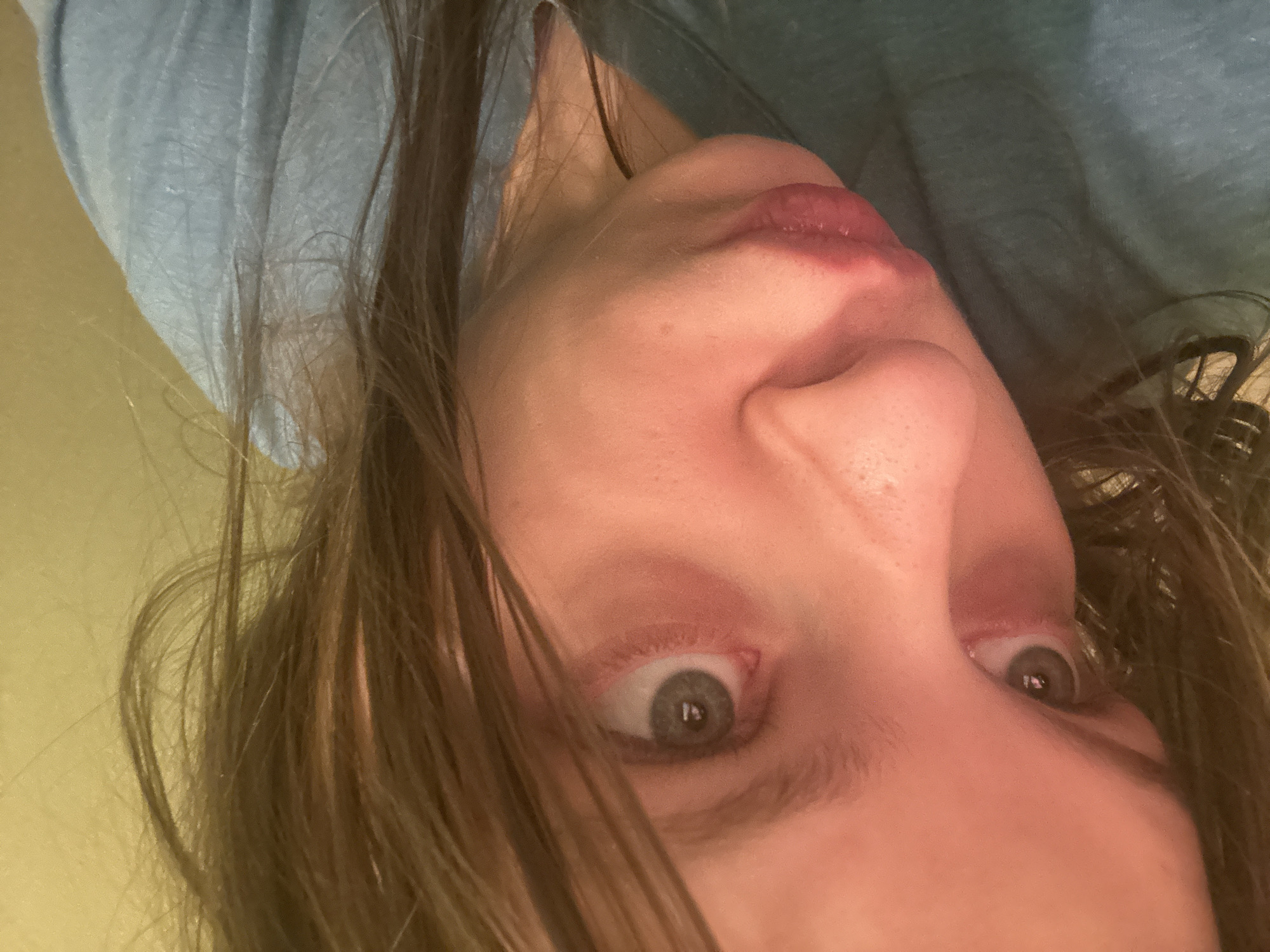 A close-up, upside-down portrait of a woman's face dominates the image. Her eyes are wide and gray-green. The skin is light. The hair is brown and falls across her face. She wears a blue shirt. There is no indication of Moscow, Russia, in the image.