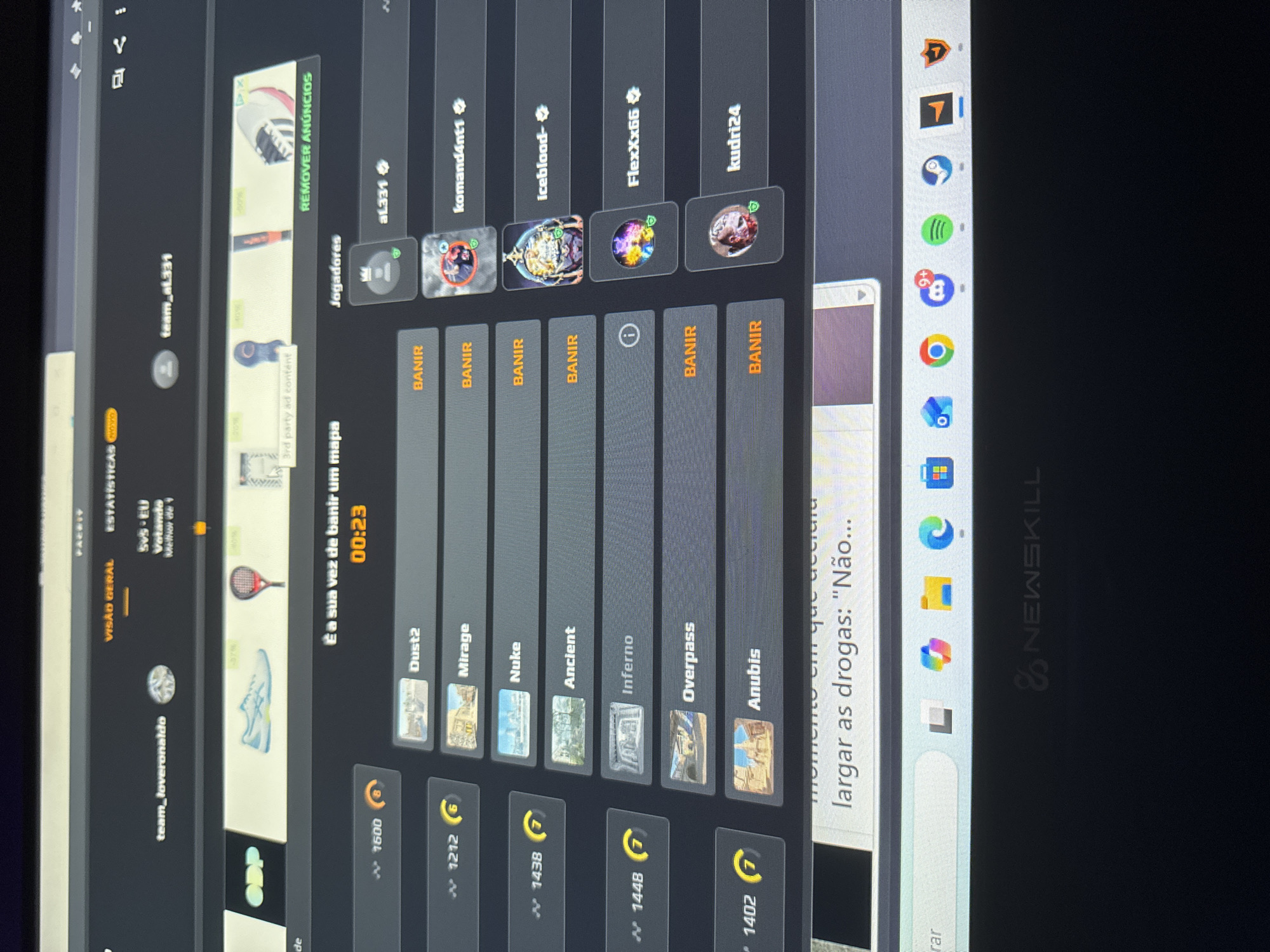 The image shows a computer screen displaying an online game interface. The user "team_loveronaldo" is in the "VISAO GERAL" (general view) of the "ESTATISTICAS" (statistics) section. It is a 5v5 game ("SVS-EU"), where "team_loveronaldo" is voting ("Votando") for "Melhor de" (Best of). The interface shows the map ban phase, with a timer reading "00:23" and the text "É a sua vez de banir um mapa" (It's your turn to ban a map). Available maps for banning are displayed as "Dust2," "Mirage," "Nuke," "Ancient," "Inferno," "Overpass," and "Anubis," each with a cost in currency. The players listed are "aL331," "komand4nt1," "iceblood-," "FlexXx66," and "kudri24." Banning options ("BANIR") are available for each player except "FlexXx66," which displays an information icon. The screen also shows third-party ads.
The taskbar has icons for Chrome, Spotify, Microsoft Teams, and other applications. There is an open web browser with text reading "momento em que decidiu largar as drogas: 'Não...' (moment when decided to quit drugs: 'No...')." The computer is a Newskill brand laptop. The image does not contain any information relating to Mirandela, Portugal.