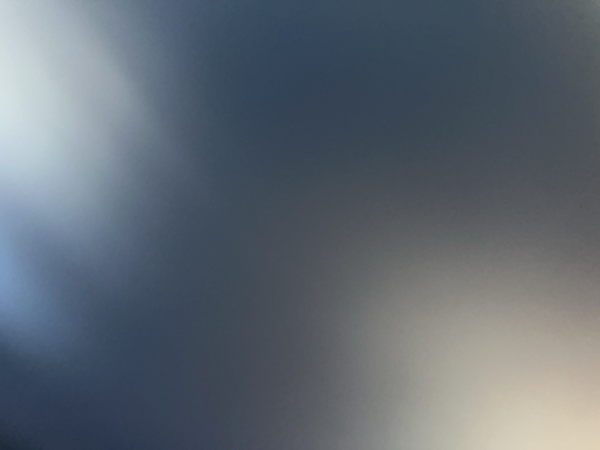 This media file is an abstract image characterized by a gradient of blues and grays, with areas of bright white light. There are no discernible people, objects, or specific scene details. The image appears to be a close-up of a surface with a diffused lighting effect, creating a blurred and indistinct visual. The bright white light on the left side suggests a strong light source, possibly the sun, casting a soft glow across the darker, blue-gray background. The texture of the surface is not clear due to the blurriness. There is no visible text. The overall impression is one of abstract light and color, lacking any concrete subject matter or narrative. The context of Belgrade, Serbia, does not provide any direct visual cues within the image itself.