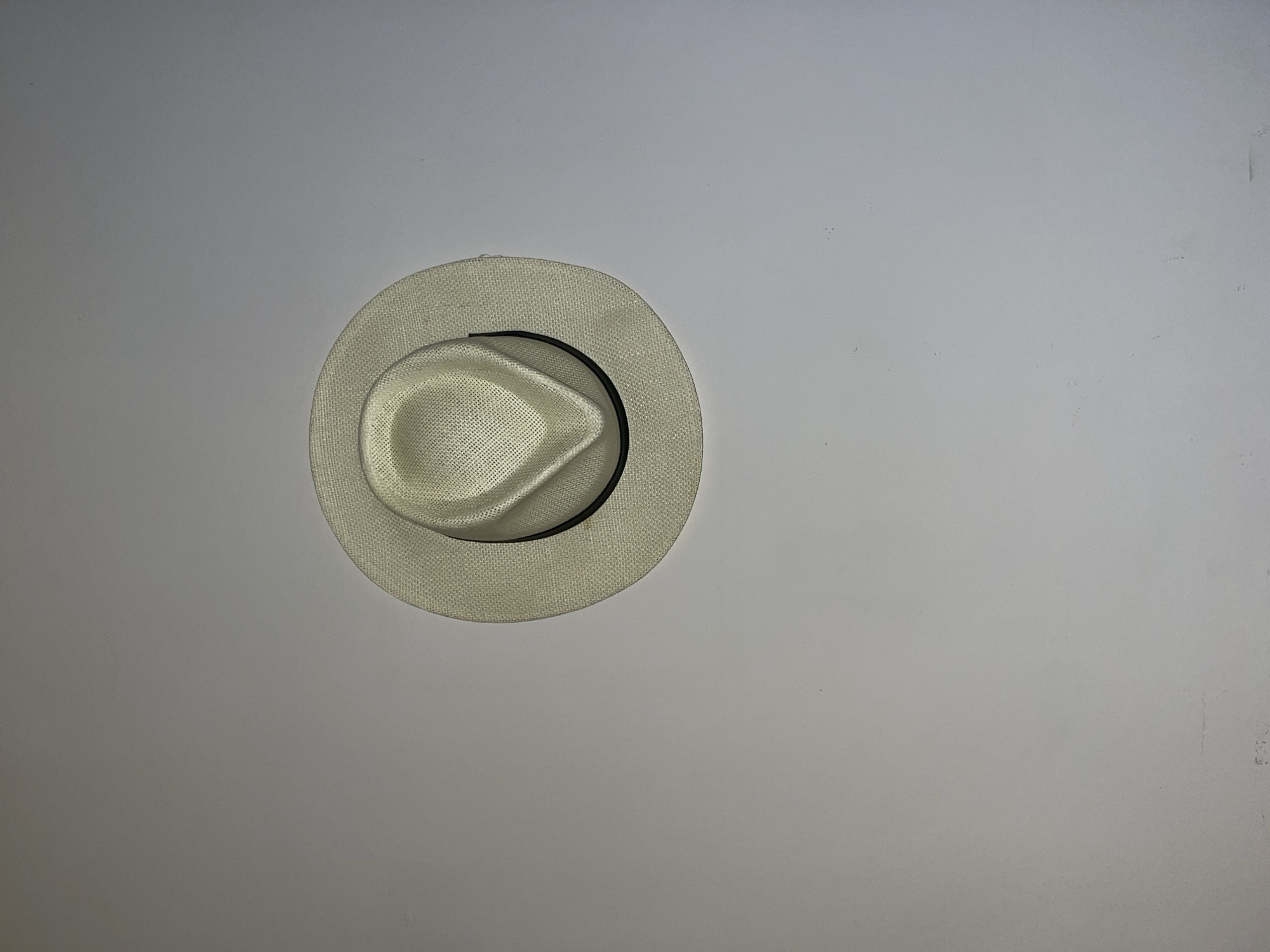 A white straw Panama hat with a black band sits on a plain white or light grey surface. The hat is centrally positioned towards the left side of the image, with empty space occupying the right side. The location in Torrent, Spain is not discernible from the image.