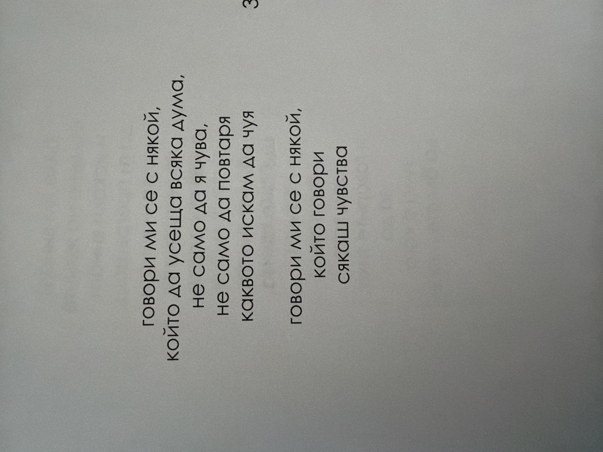 The image is a close-up, overhead shot of a page from a book. The page has text printed on it in a dark, sans-serif font against a textured, light gray background. The text appears to be poetry, written in Bulgarian. There is also a number "3" printed on the right side of the page. The image does not contain any information about the city of Pazardzhik, Bulgaria.