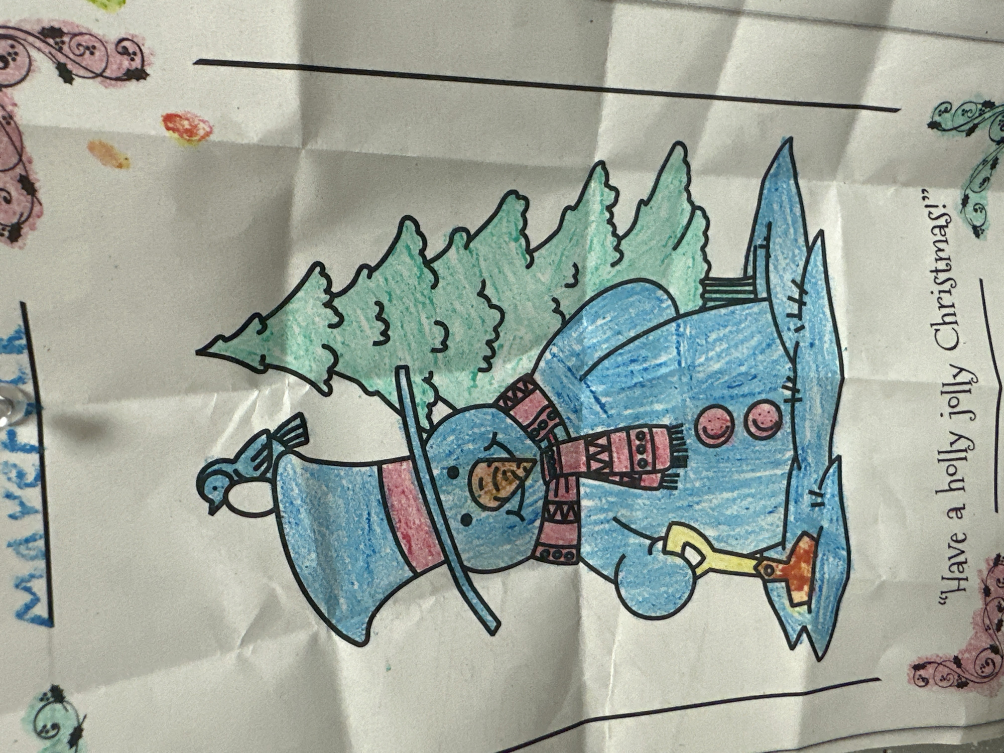 The image displays a hand-drawn picture of a snowman wearing a top hat and scarf, standing next to a Christmas tree. The snowman is holding a shovel. The drawing is colored with crayons and appears to be on crumpled paper. Text at the top of the image reads "Maverick" and at the bottom reads "Have a holly jolly Christmas!". Decorative elements are present on the sides. The image does not provide any information about the city of Harrisburg, United States of America, or any specific location.