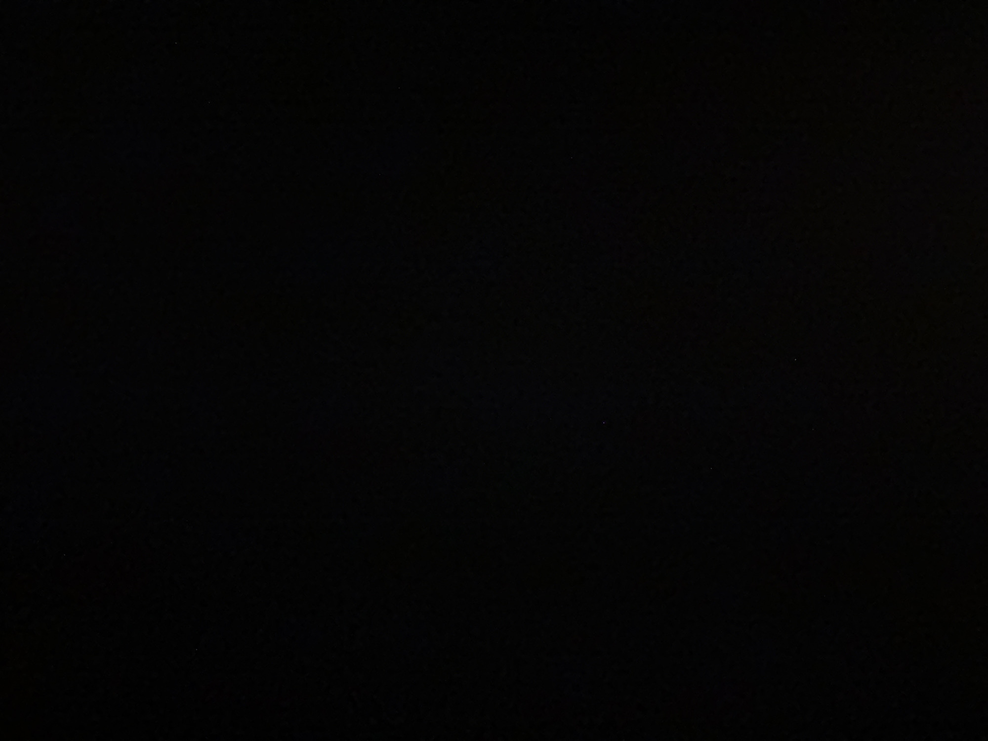 The image displays a uniformly dark, almost entirely black field, indicating either extreme underexposure or a scene devoid of light. No discernible subjects, objects, people, or actions are identifiable within the frame. Minimal variations in pixel brightness are present, manifesting as extremely faint, indistinct darker and lighter specks or subtle texture consistent with digital noise or ambient light in near-total darkness. The visual content offers no specific features or context to identify a particular location within the city of Mirovyane, Bulgaria, from which this image is stated to originate.