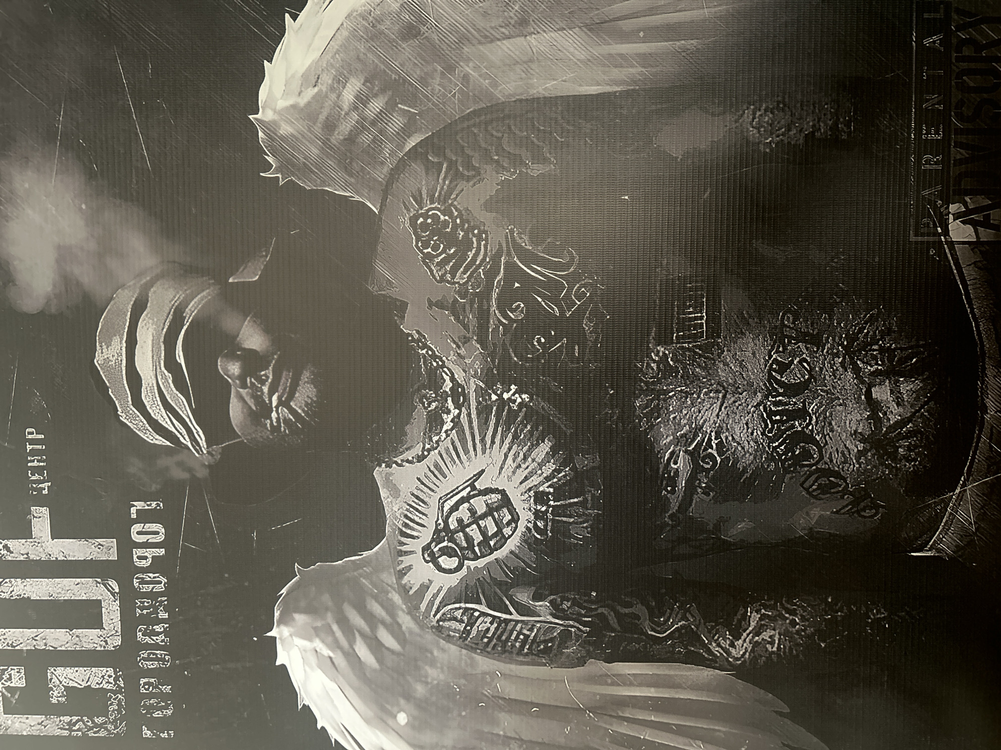 A black and white image, rotated 90 degrees counter-clockwise, depicts a man with angel wings and extensive tattoos smoking. The man is bald and appears to be holding a cigarette in his mouth, with smoke emanating from it. Visible tattoos include a grenade design on his chest. Text is present on the left side of the image, including "Guf" in large letters. Additionally, "Parental Advisory" text is visible on the right side. The environment is indeterminate due to the graphic style and limited context. The location is listed as "Unknown, Unknown."