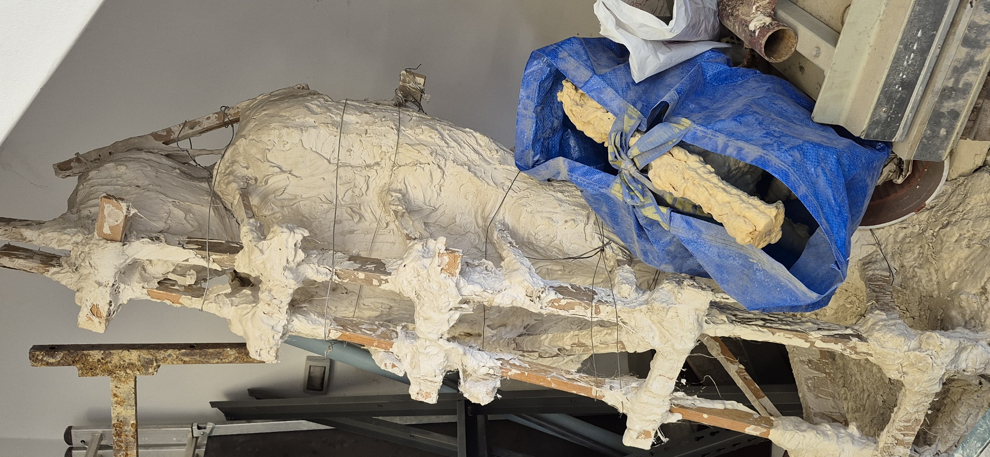 An interior view, taken at an upward angle, reveals what appears to be an unfinished or damaged structure, possibly a ceiling or architectural detail. The structure is composed of what appears to be a combination of wood, plaster, and wire, giving it a rough and textured appearance. A blue plastic tarp partially covers the structure.
The exact location in Cetinje, Montenegro, is not discernible from the image. No people, specific actions, or interactions are visible in the image.