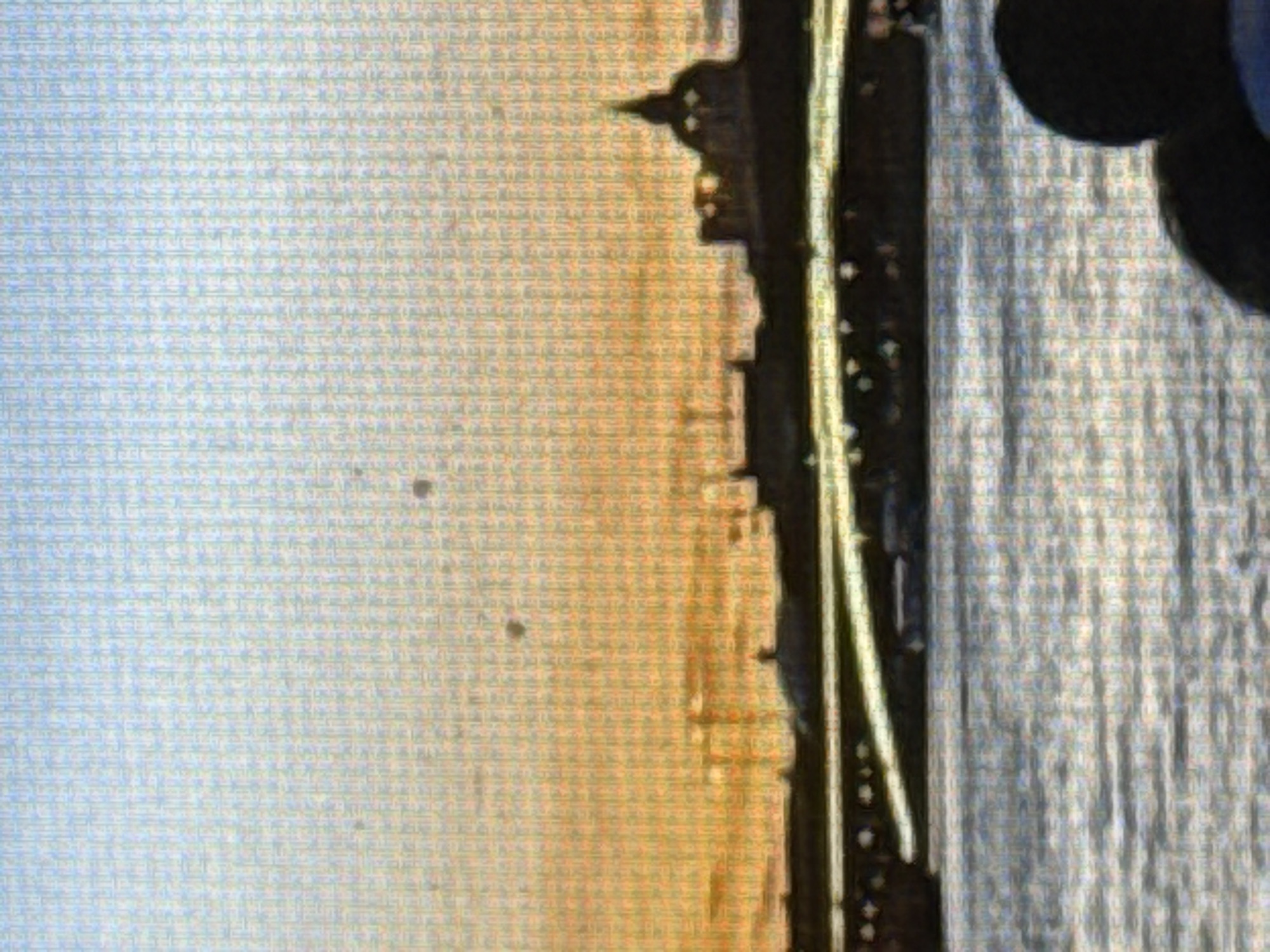 A wide shot captures a hazy, sunset sky over a body of water, possibly a river or bay. The sky transitions from a soft blue at the top to a warm orange and yellow as it approaches the horizon. Faint, dark circles are visible in the sky, appearing as distant objects.
A dark silhouette of a city skyline stretches across the midground. Notable structures include a prominent dome with a spire, likely a church or government building, and a long, horizontal structure resembling a bridge or embankment with visible arches and lights. Some smaller buildings and structures are also silhouetted against the sky.
The foreground is dominated by a body of water with gentle ripples reflecting the sky's colors. In the lower right corner, the backs of two individuals are visible, facing away from the camera and towards the city skyline. Their figures are dark and indistinct, suggesting they are seated or standing close together. One person has dark, curly hair, and the other appears to be wearing a blue garment. The overall impression is one of a peaceful, urban sunset scene observed from a vantage point on the water.