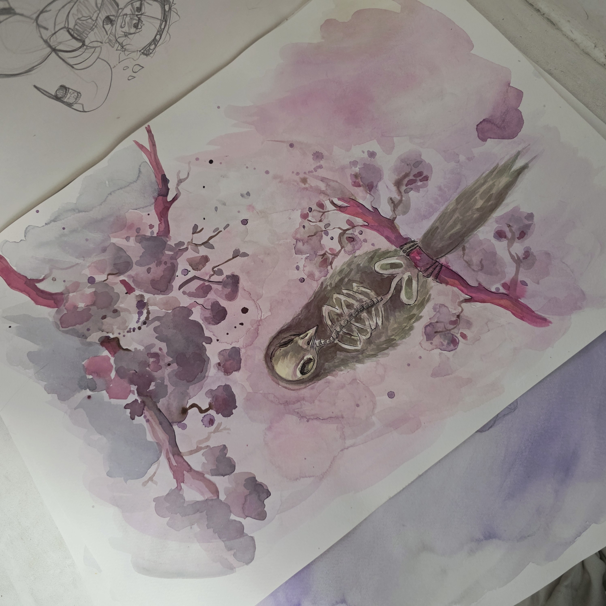 The image is a watercolor painting of a dead bird skeleton hanging from a branch with cherry blossoms. The background is a wash of pinks and purples. The overall style is somewhat melancholic and surreal. The location is not depicted, and it is not possible to determine if it is Saint Petersburg, Russia. In the top left corner of the image, there is a rough sketch of an anime-style character.