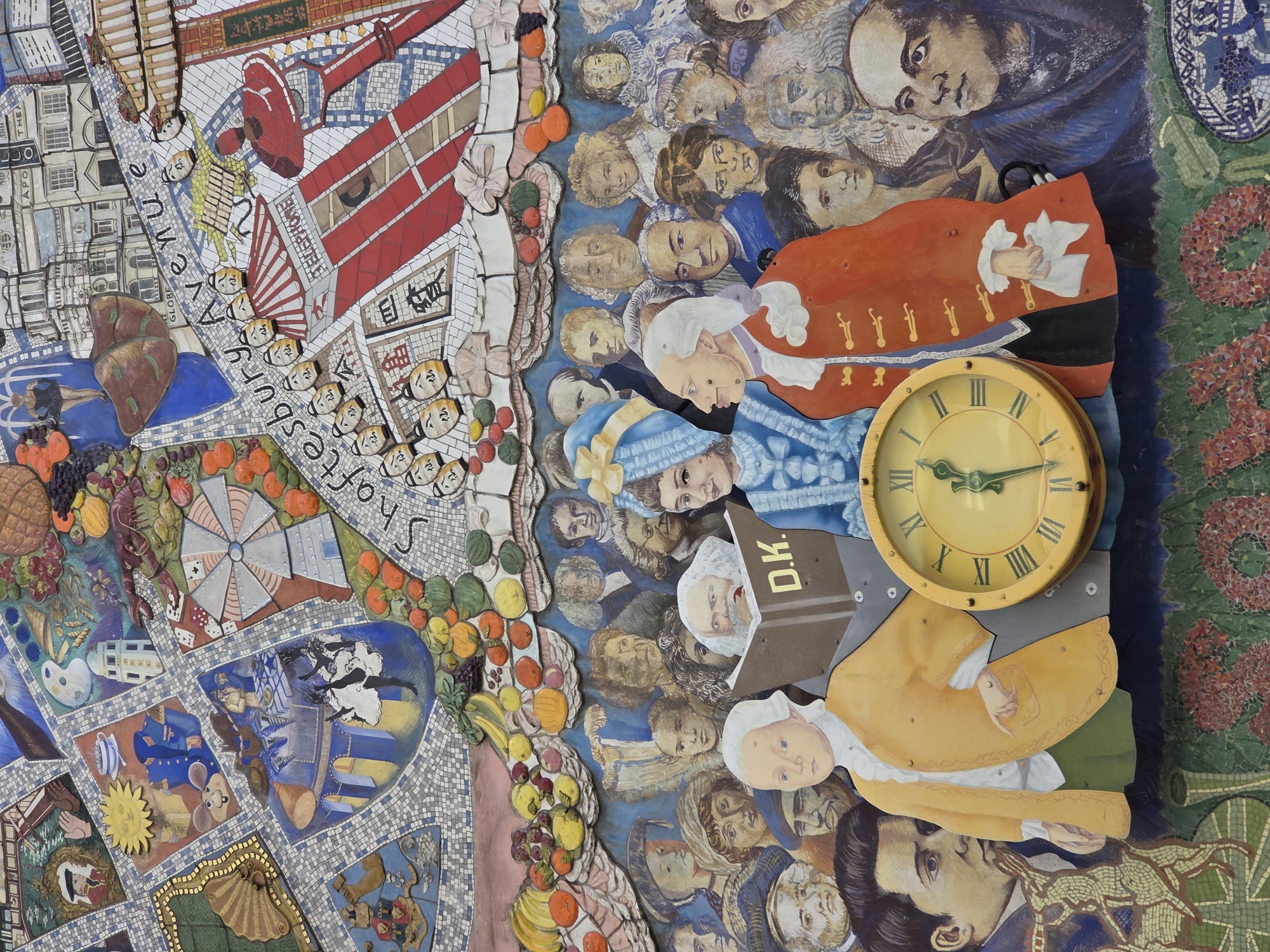 This is a detailed image of the ceiling mosaic at the Seven Dials roundabout in London, United Kingdom. The mosaic is composed of various images depicting aspects of the area's history, landmarks, and culture.
On the left side, there's a depiction of Shaftesbury Avenue with miniature face masks, a stylized view of a red building, and various objects interspersed among fruits, vegetables, and seafood.
On the right, a multitude of faces with wigs and historical costumes are visible. A yellow clock with roman numerals sits atop this section, positioned over a figure in an orange coat.
The overall composition is a vibrant and complex piece, showcasing the rich and diverse characteristics of the Seven Dials area.