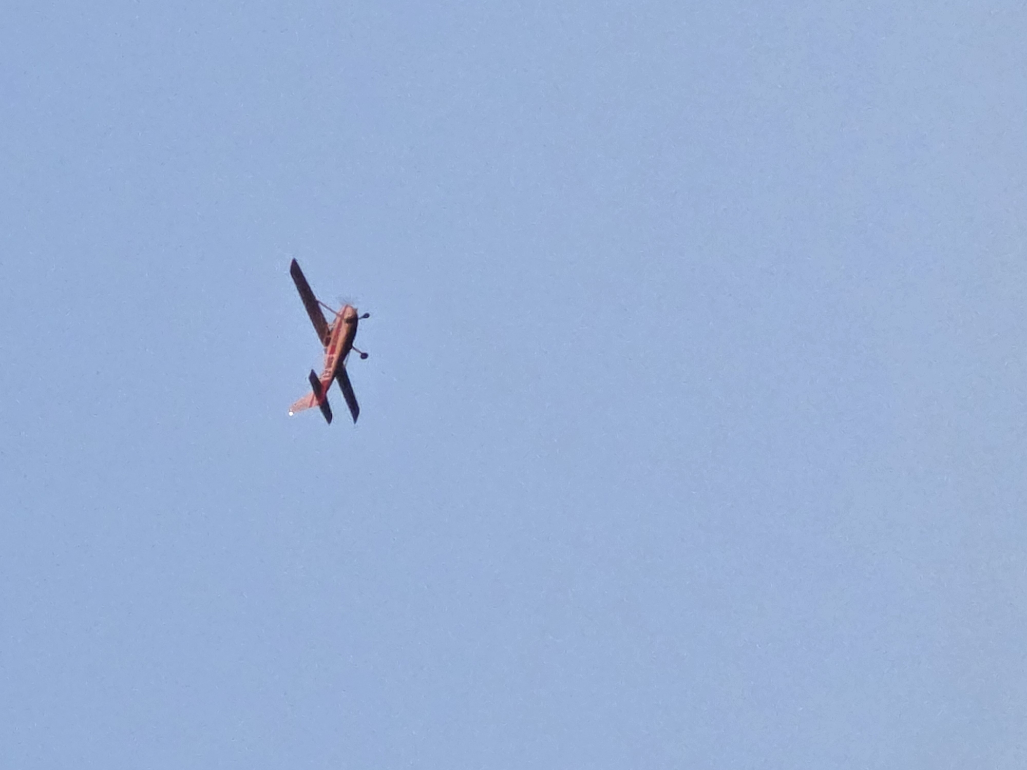 A red biplane is flying in a clear, blue sky. The location cannot be determined to be in the city of Yagodovo, Bulgaria, based on the image content.
