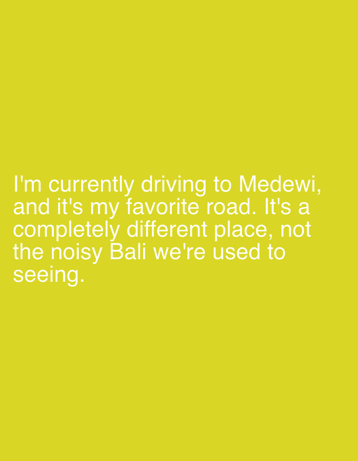 The image is a solid yellow background with white text in the bottom left corner. The text reads: "I'm currently driving to Medewi, and it's my favorite road. It's a completely different place, not the noisy Bali we're used to seeing."