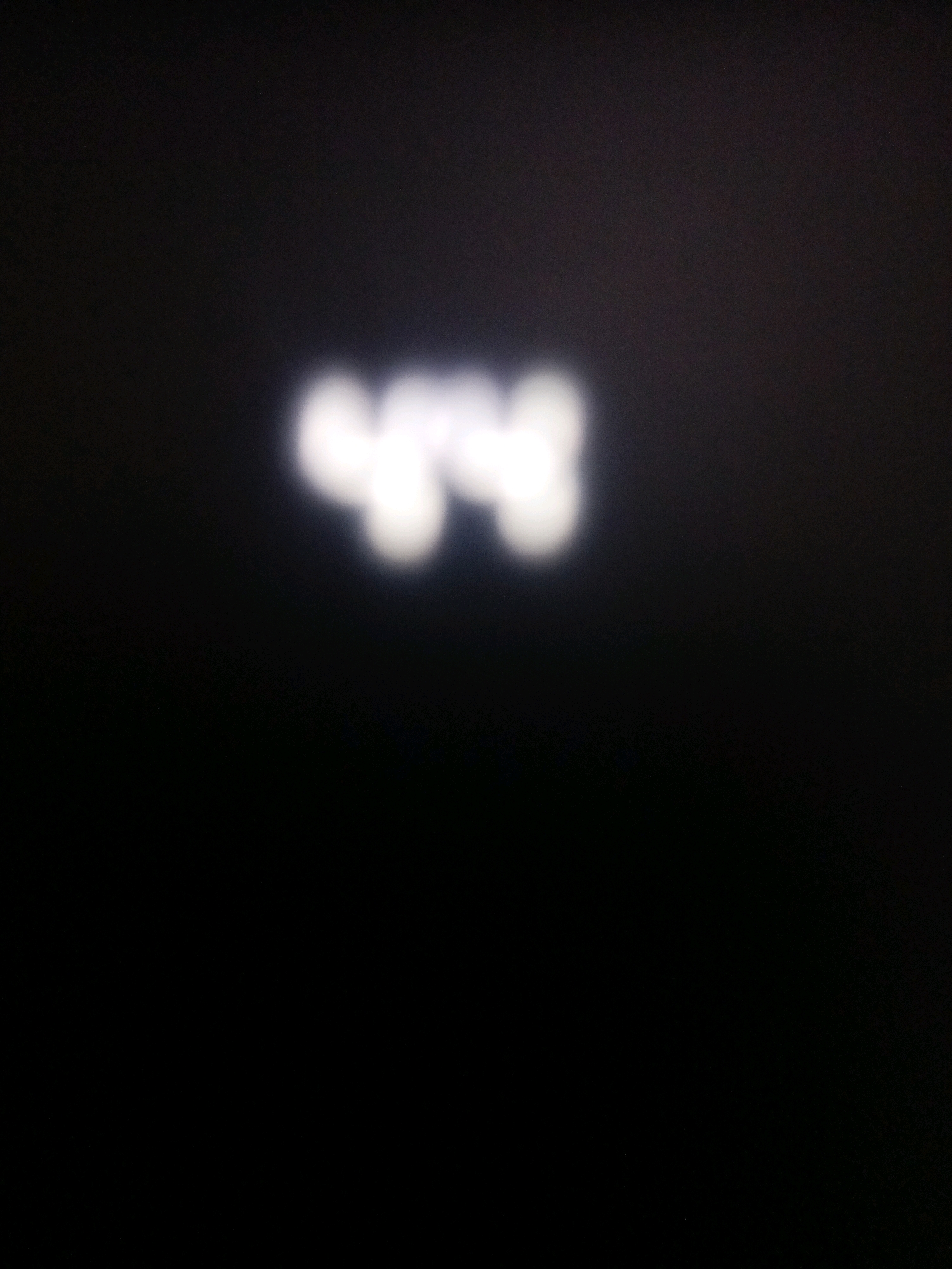 The image shows blurred white text on a black background. The text appears to be the numbers "448". The image has a very low resolution and is out of focus, making it difficult to discern any specific details about the origin or context of the text. There is no information in the image that can be used to determine its location in the city of Surabaya, Indonesia.