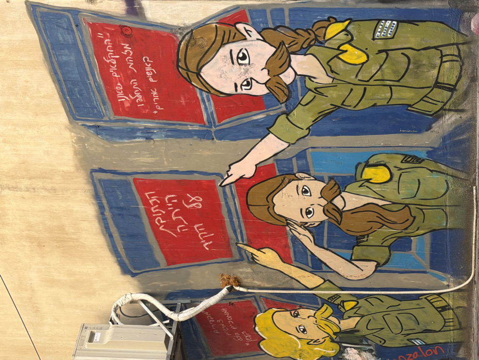 A mural is painted on a textured beige wall in Tel-Aviv, Israel. The artwork depicts three cartoonish female figures, shown from the waist up, all wearing green military-style uniforms with yellow shoulder epaulets and prominent brown mustaches. The leftmost figure, with blonde hair, points upwards with her right index finger. The middle figure, with brown hair, performs a military salute with her right hand. The rightmost figure, with brown hair and a visible braid, extends her right arm and index finger forward/upward, displaying an Israeli flag patch on her left sleeve. Behind the figures are three stylized blue and gray rectangular frames, each containing a red panel with white Hebrew text. The left panel reads: "התקוה הייתה על הקיר" (The hope was on the wall). The middle panel's text is partially legible as "מזלון / מה את עושה?" (Mazalon / What are you doing?). The right panel reads: "החוקים שונו. המלחמה התחילה. אנשים אחרים." (The rules have changed. The war has begun. Other people.). An external air conditioning unit is mounted on the upper left portion of the wall, with a white corrugated drainage pipe extending downwards, passing in front of the leftmost and middle figures. A faint signature "ozelon" is visible near the left figure's left shoulder.