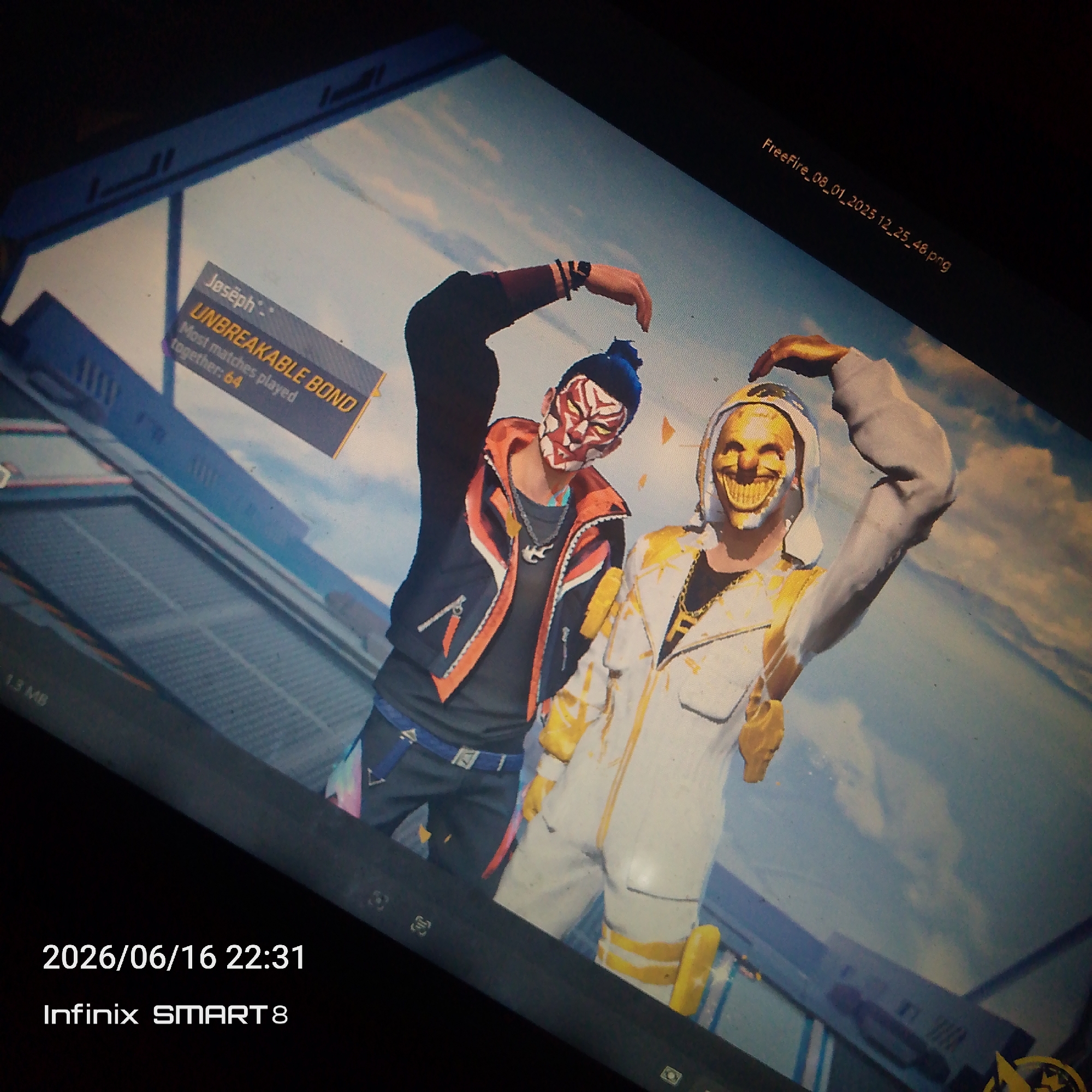 A medium shot captures two individuals in a video game, likely Free Fire, set against a bright blue sky with clouds. The person on the left wears a black jacket with orange accents, a black shirt, and a red and white mask, with their right arm raised in a heart shape. The person on the right is dressed in a white and gold outfit, also with a gold mask featuring a grinning face, and their left arm is raised in a heart shape. A text overlay on the left side of the image reads "Joseph" and "UNBREAKABLE BOND" with "Most matches played together: 64" below it. A file name "Freefire_08_01_2023_12_25_48.png" is visible in the upper right corner. The bottom of the image displays the date "2026/06/16 22:31" and "Infinix SMART 8", indicating the capture device and time. The scene appears to be a celebratory in-game moment.