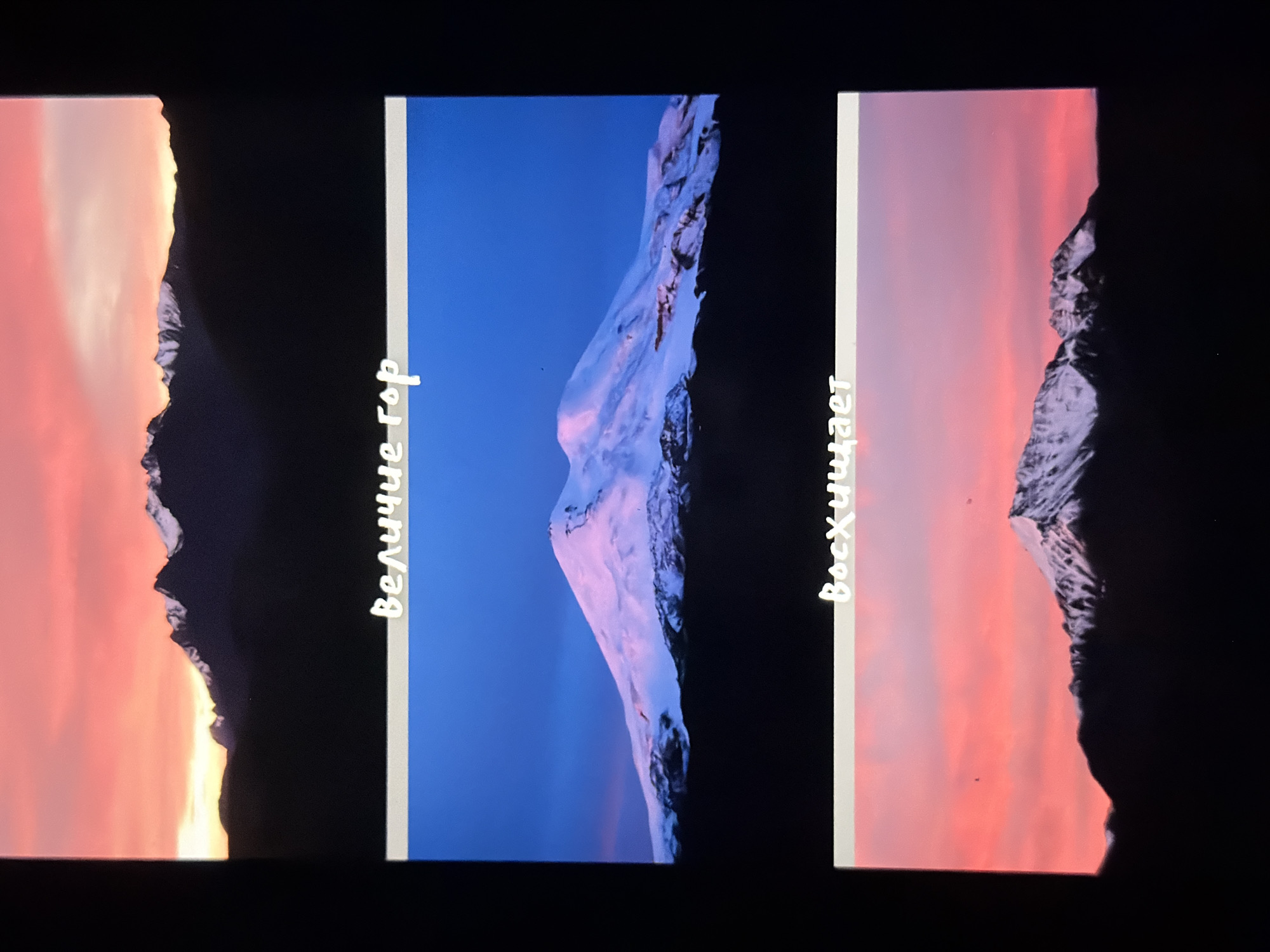 The image displays three distinct scenes of mountains at different times of day, each with superimposed white Cyrillic text. The top and bottom images show mountain ranges silhouetted against a vibrant pink and orange sunset sky. The middle image features a large, snow-capped mountain against a deep blue sky.
The text in the top image reads "Величие гор" (Velichie gor), which translates to "The grandeur of mountains."
The text in the middle image is partially obscured by the mountain itself but appears to be a single word in Cyrillic.
The text in the bottom image reads "Восхищает" (Voskhishchayet), which translates to "Inspires awe" or "is admirable."
The overall presentation suggests a collection of images intended to evoke a sense of wonder and appreciation for mountainous landscapes. There is no information present in the image that would allow for the determination of the specific location within the city of Krasnodar, Russia, as Krasnodar is a city and not a mountainous region.