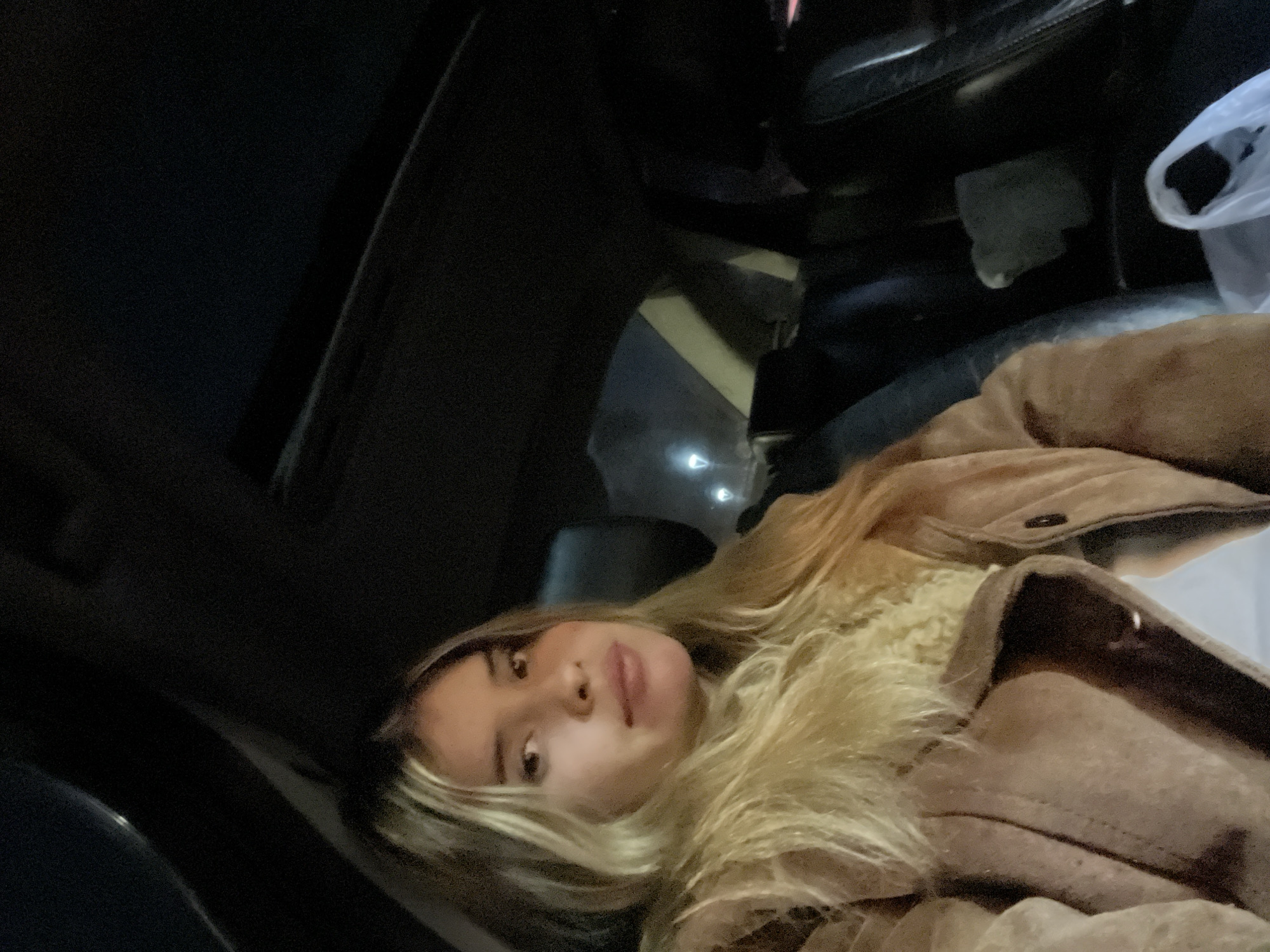 A blonde woman in a brown jacket is sitting inside of a car. The location is unknown, and the city of San Fernando del Valle de Catamarca, Argentina, cannot be determined.