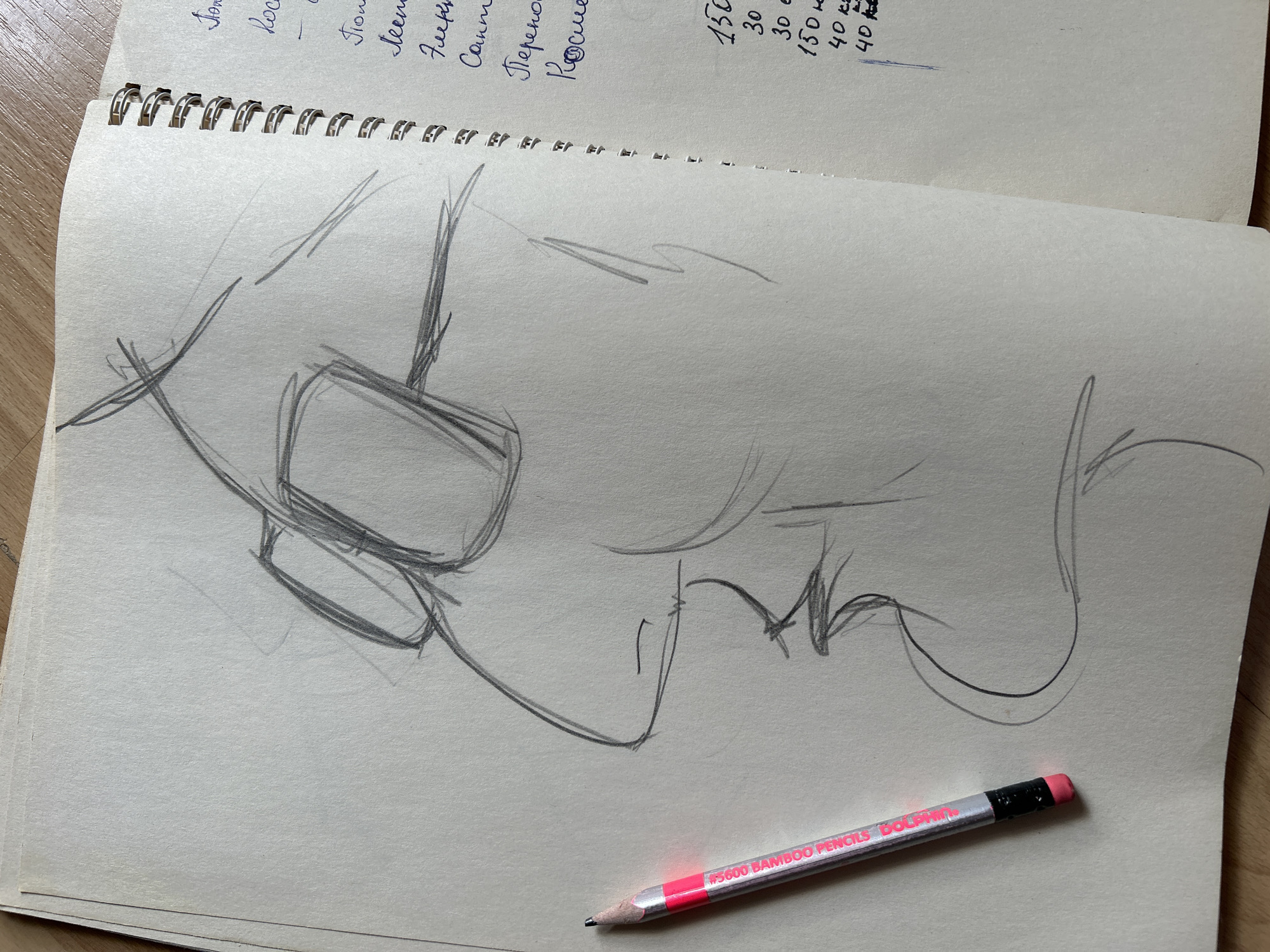 A pencil sketch of a person's profile, wearing glasses, is visible in a spiral-bound notebook. The sketch is on the left page, with a pencil lying on it. The right page contains handwritten text in Russian, including numbers and what appear to be measurements. The notebook is open on a wooden surface. The text on the right page includes "150", "30", "30", "150", "40", and "40" followed by units that are difficult to discern, possibly related to currency or quantity. Some of the Russian words include "Поме", "Космо", "Лен", "Сам", and "Перено". Based on the context of the Russian text and the visible elements, the scene is likely an artist's sketchbook. However, there is no information present in the image that would allow for the precise location in the city of Moscow, Russia to be determined.