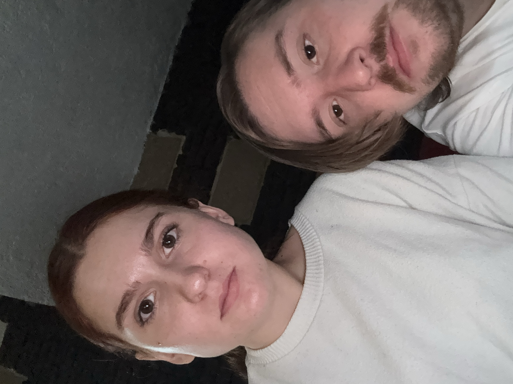 Two people are in the frame. A woman with brown hair and a white sweater is on the left. A man with brown hair and a beard is on the right, also wearing a white shirt. The background is a wall. The location is Cañada de Madero, Mexico.