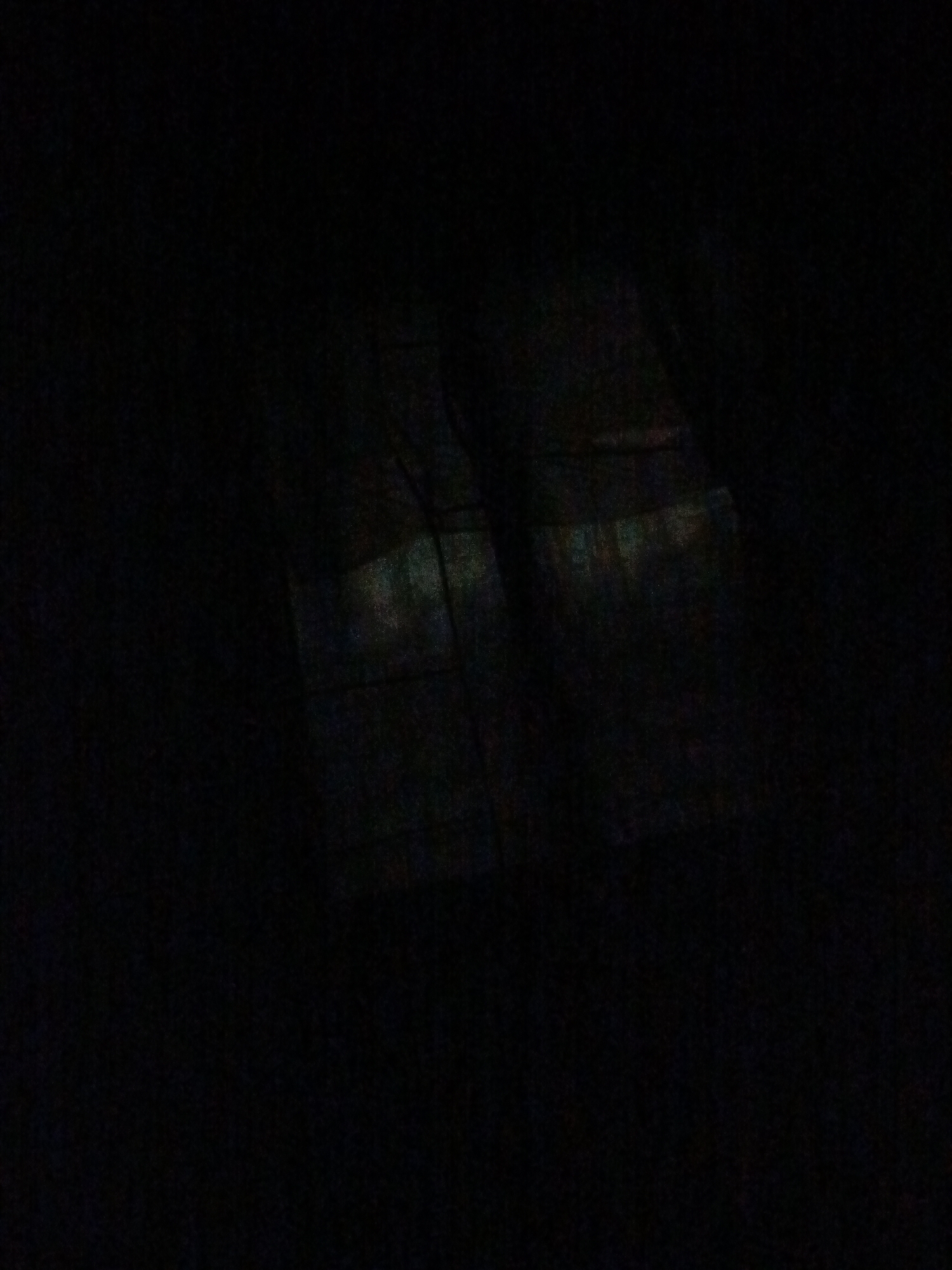 The image appears to depict a window in a dark or dimly lit room. The window is composed of several panes, as indicated by the visible grid-like pattern. The glass seems to have a slightly iridescent quality. There is no clear indication of the location being Juan Griego, Venezuela from the image alone.