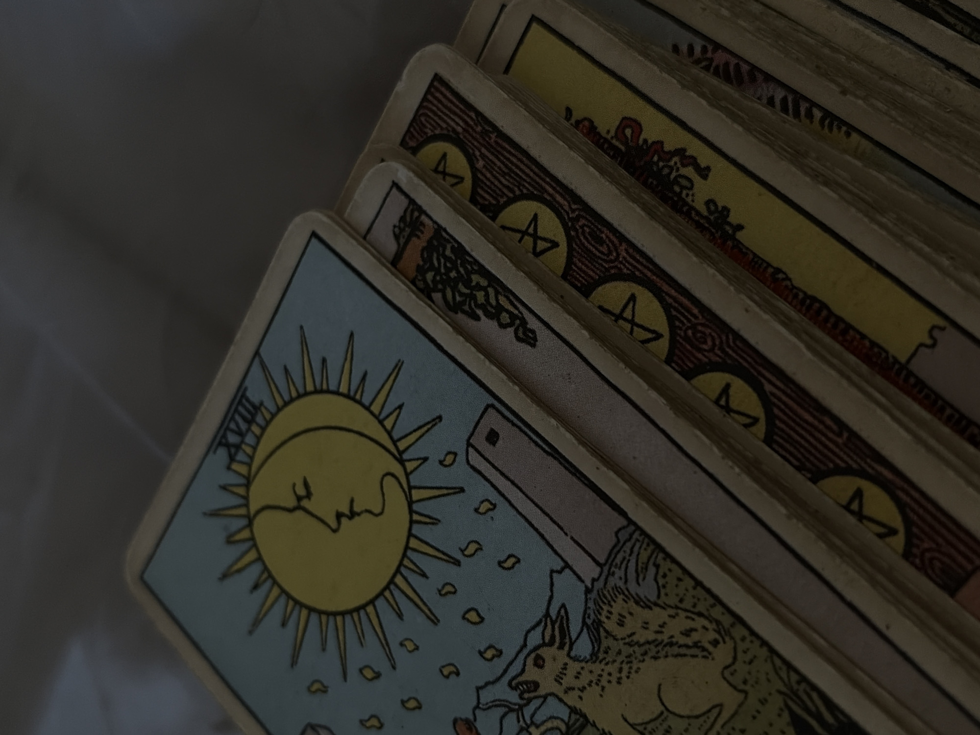 The image shows a stack of Rider-Waite tarot cards. The top card is "The Sun" (card XIX). The cards beneath it show suit of Pentacles (coins). The location in Chaikovsky, Russia is not discernable.