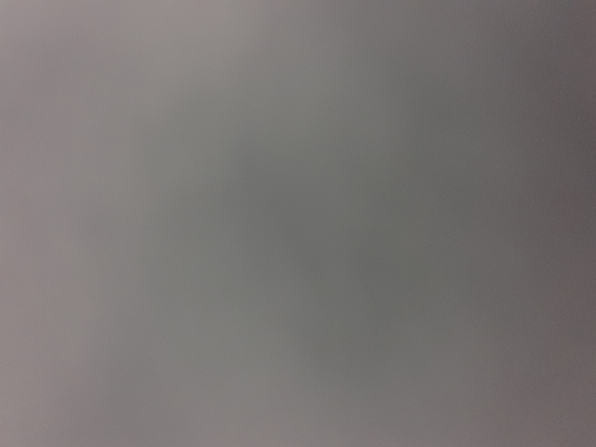 The image is a plain, gray, textured background with a subtle gradient, darker at the top and lighter towards the bottom. No objects, people, or environment details are visible. The image is a uniform color and texture.