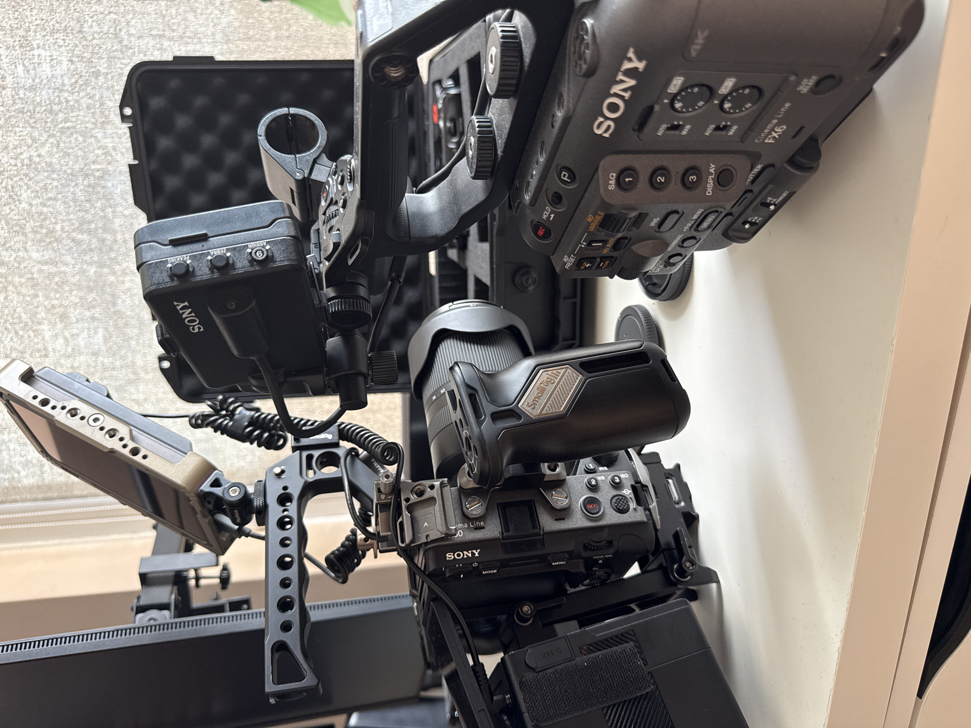 This image depicts a complexly rigged Sony FX6 Cinema Line camera system. The camera is equipped with various accessories including a lens, handle, SmallRig components, an external monitor, and a D-Tap power source. It is unclear what city this photograph was taken in.