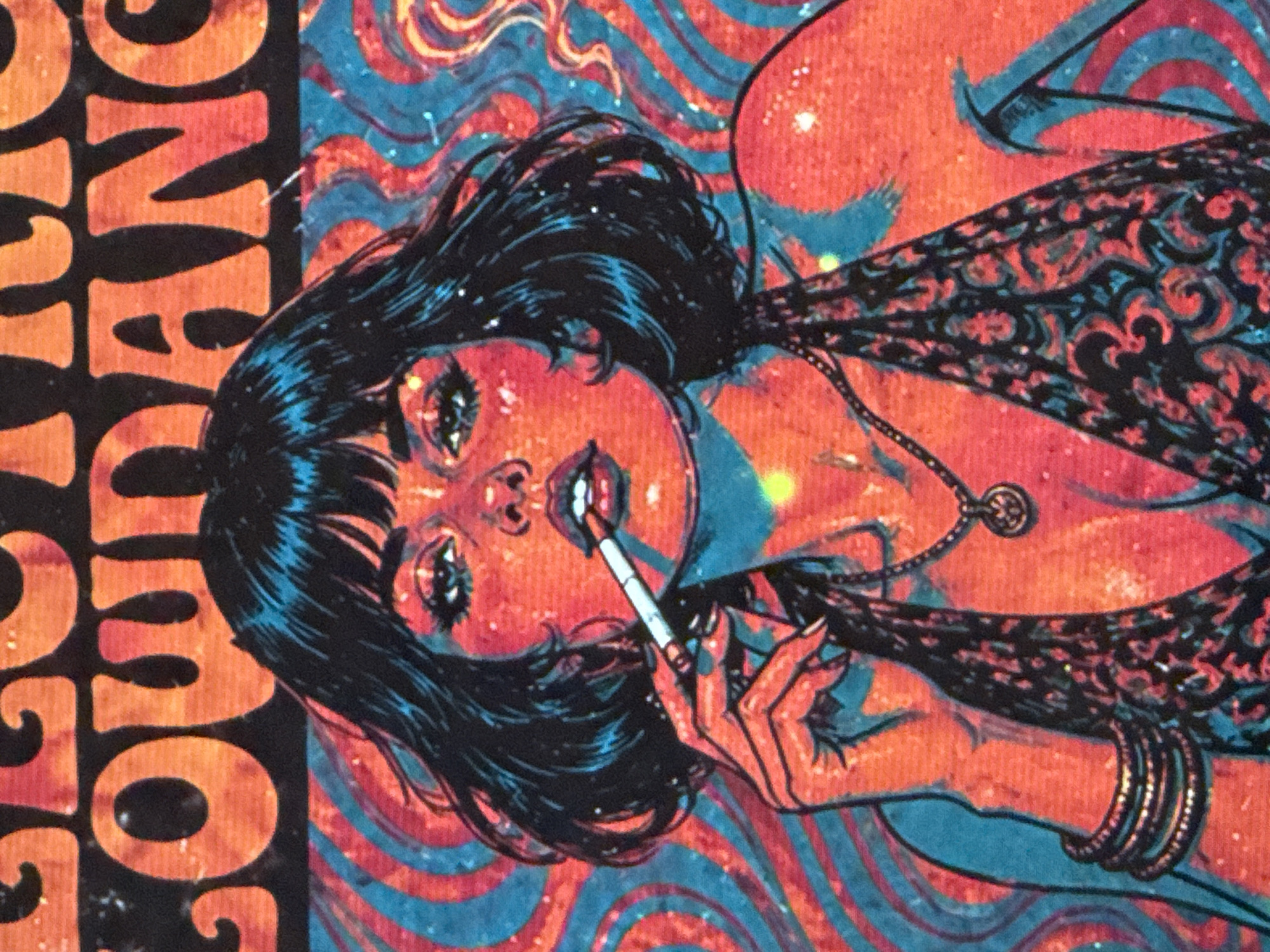 A close-up, angled shot displays a digitally stylized image of a reclining woman smoking a cigarette. She has dark hair with a blue sheen, and fair skin rendered in shades of orange and red. Her head is turned to face the viewer. She is wearing a patterned shawl or dress and multiple bracelets. A necklace with a circular pendant is visible. The background features swirling patterns in blue and orange. Fragment of text reading "YOUNG" is visible on the left edge. The image does not provide any information suggesting that it is set in Đà Nẵng, Vietnam.
