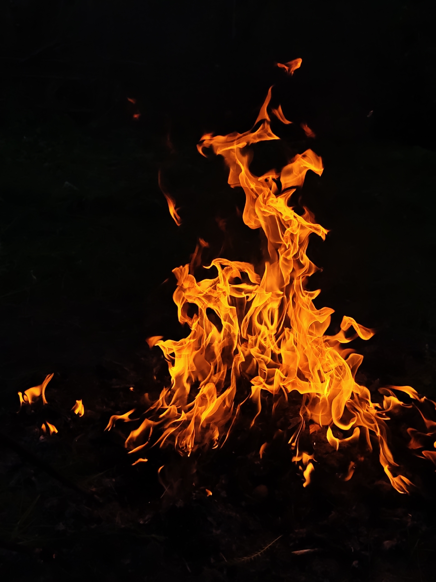 A bright orange and yellow fire burns against a stark black background. The flames are concentrated in the center of the image, reaching upward with flickering tips. The environment surrounding the fire is dark and indistinct. The location and presence of Parkhomivka, Ukraine is unknown.