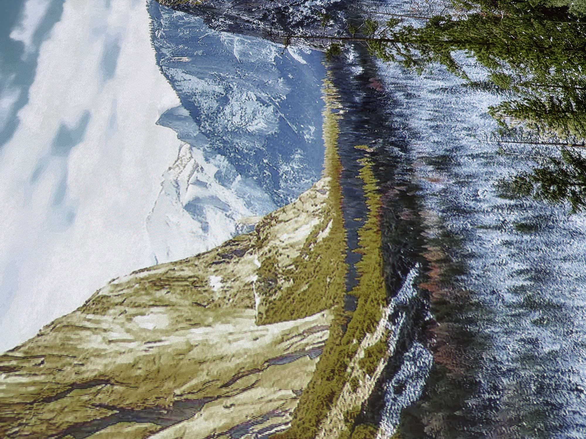 The image depicts a majestic mountain landscape, likely Yosemite Valley, in California, United States of America. The foreground is dominated by a snow-covered forest of evergreen trees, with some deciduous trees showing touches of red and yellow foliage, suggesting a transition between autumn and winter. Towering granite cliffs rise dramatically on the left, their surfaces textured and weathered. In the background, snow-capped mountains recede into the distance, shrouded in a hazy sky with scattered clouds. The overall scene conveys a sense of vastness, natural beauty, and the crisp atmosphere of a cold, mountainous environment. There are no people or discernible man-made structures visible in this natural landscape. The image has a painterly quality, with visible brushstrokes or a textured rendering style.