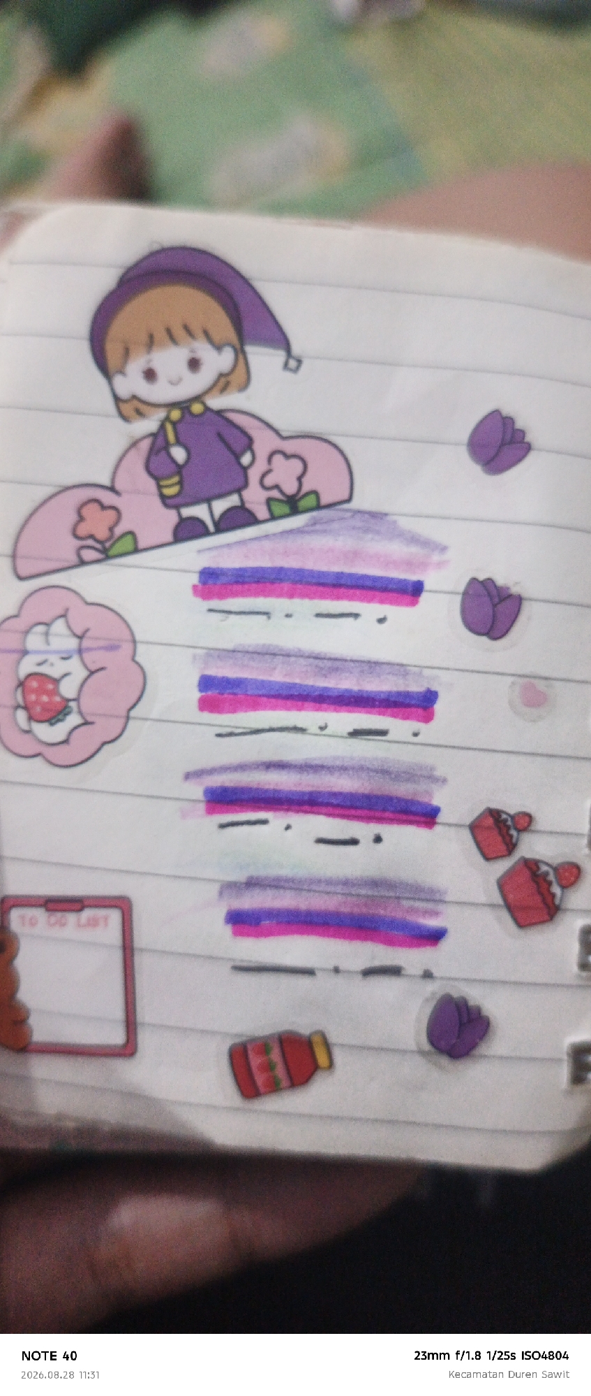 The image is a close-up, slightly blurry photograph of a notebook page adorned with various stickers and colorful marker lines. Dominating the top center is a sticker of a cartoon girl with orange hair and a purple hat and dress, standing on a pink cloud with a flower. To the left of the girl, there's a sticker of a pink cloud-shaped creature holding a strawberry. The notebook page has horizontal lines, and several sections are filled with horizontal bands of marker ink in shades of purple, pink, and blue. To the right of the girl are two purple tulip stickers. Below the tulip stickers, on the right side of the page, are two red cupcake stickers with white frosting. Near the bottom left, there's a pink-framed to-do list sticker with the words "TO DO LIST" printed inside. Below that, there's a red bottle sticker with three pink slices. The bottom of the image shows a meta-data tag with "NOTE 40", "2026.08.28 11:31", "23mm f/1.8 1/25s ISO4804", and "Kecamatan Duren Sawit". This suggests the photograph was taken in the Duren Sawit district, which is located in East Jakarta, Indonesia, at approximately 11:31 AM on August 28, 2026.