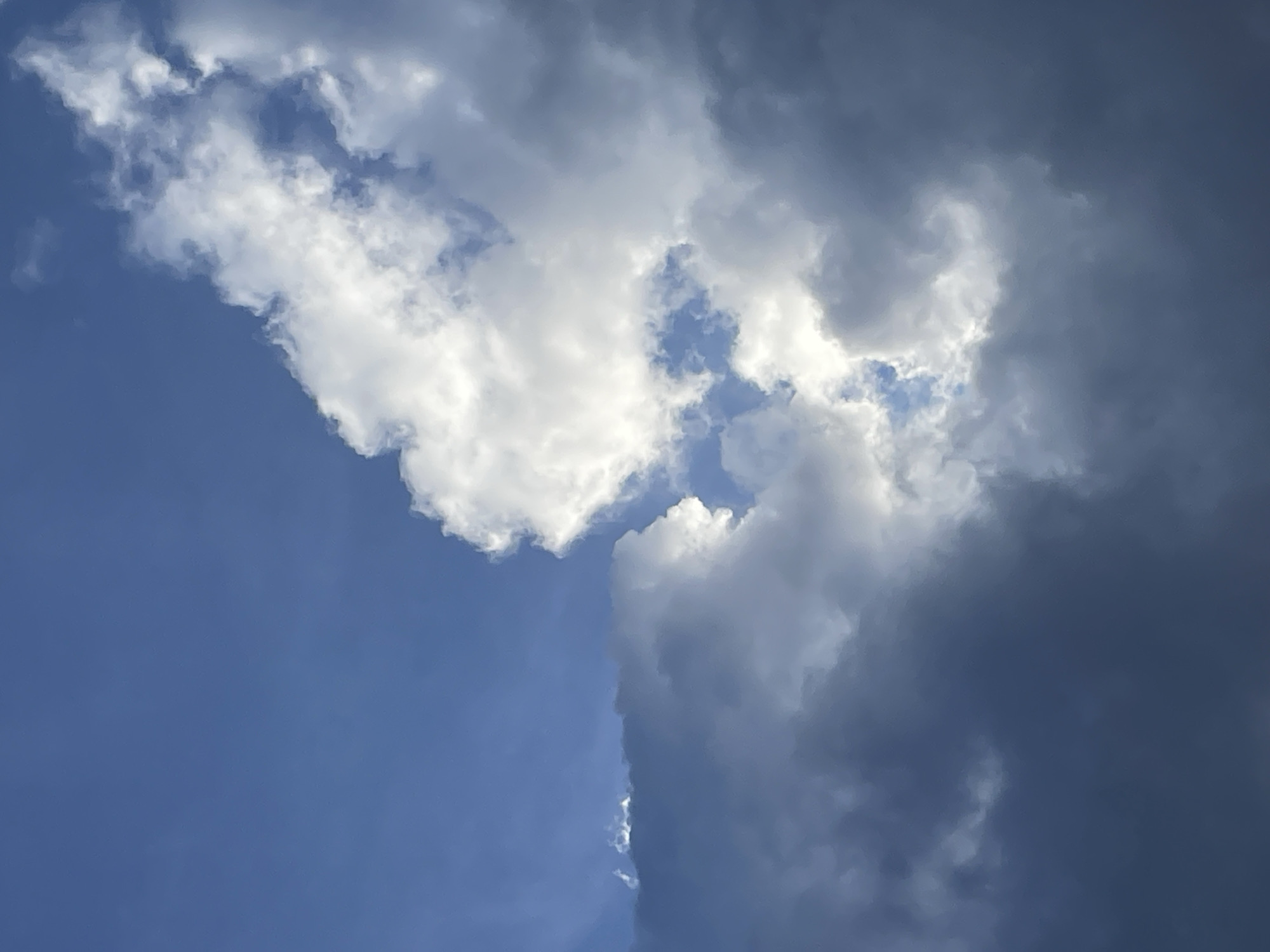 The image shows a view of the sky with white clouds against a blue background. A large, dark cloud is also visible, suggesting a potential storm. The location in the city of Moscow, Russia, is not identifiable from the given image.
