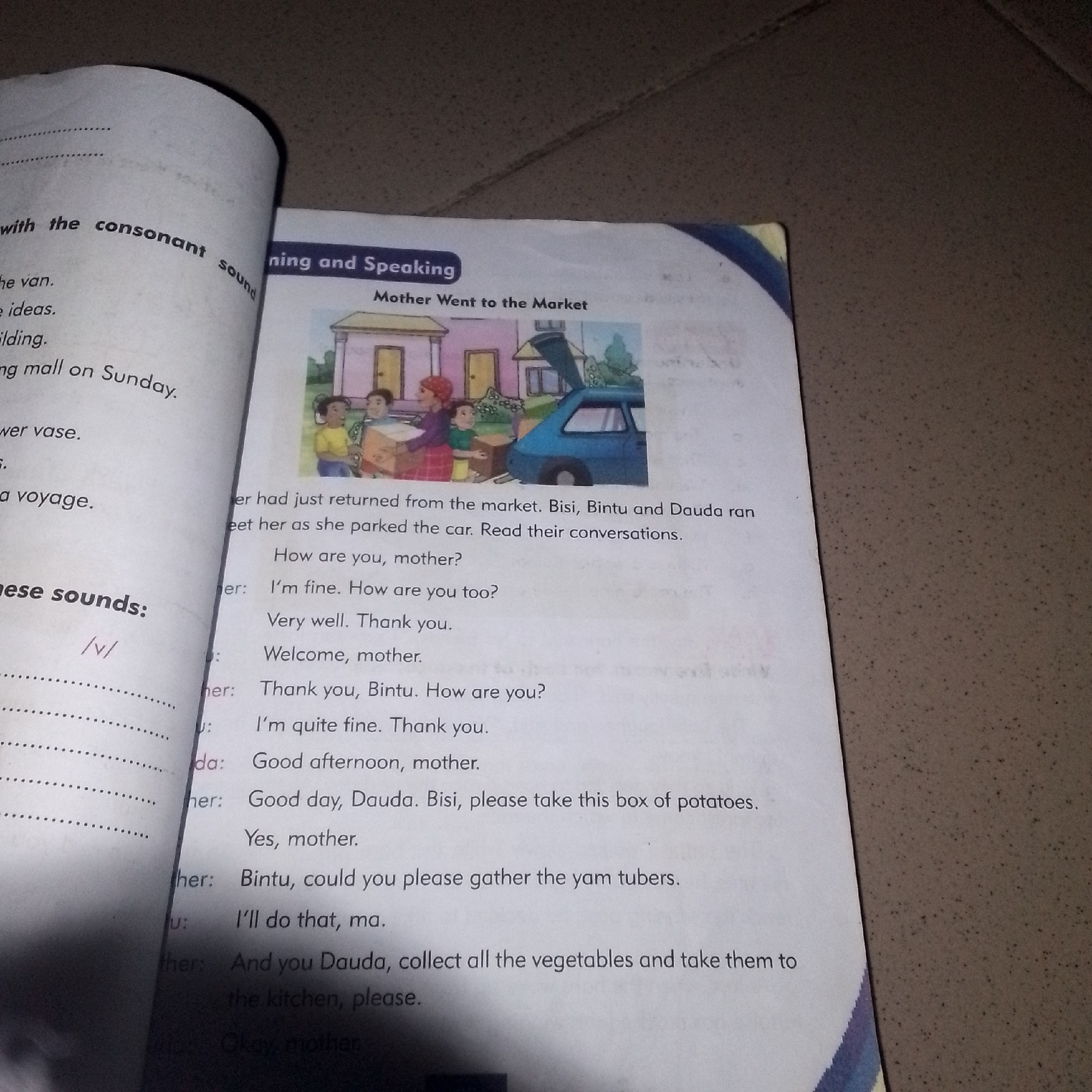 This media file is a close-up photograph of an open book, displaying text and an illustration. The book appears to be a learning resource, likely for children, as indicated by the title "Mother Went to the Market" and the illustration depicting a family scene with a car.
The illustration shows a mother, two children, and a baby near a blue car with its trunk open, implying they have just returned from shopping or are packing for a trip. The scene appears to be outdoors, with buildings and trees suggesting a residential or market area. The overall mood conveyed by the illustration is cheerful and domestic.
The text on the left page includes phrases related to "consonant sound" and lists example sentences like "the van," "ideas," "building," and "going mall on Sunday." Below this, there's a phonetic symbol "/v/" next to the heading "these sounds:".
The right page contains a dialogue between characters identified as "mother," "Bisi," "Bintu," and "Dauda." The conversation revolves around greetings, well-wishes, and instructions for carrying groceries. Phrases like "How are you, mother?", "Very well. Thank you.", "Good afternoon, mother.", and "take this box of potatoes" suggest a friendly and familial interaction. The text indicates a time of day where greetings like "Good afternoon" and "Good day" are appropriate. The mention of "yam tubers" and "vegetables" reinforces the context of shopping or preparing food.
The overall setting is likely domestic or a place where such interactions would occur, possibly in Nigeria given the names of the characters. The lighting in the photograph is somewhat dim, possibly indicating an indoor shot or a time of day with less natural light.