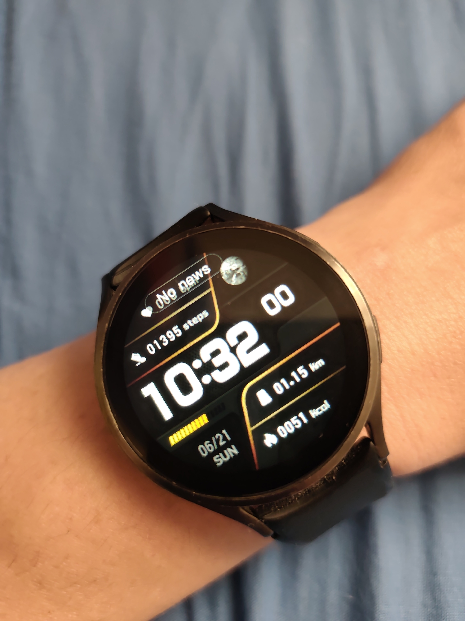 A close-up, high-angle shot shows a person's wrist wearing a black smartwatch. The watch face displays the time as 10:32, with additional information including "No news," "01395 steps," "01.15 km," and "0051 kcal." The date "06/21 SUN" is also visible. The background is a blurry, textured blue fabric. The image does not provide any information about the location in Stare, Ukraine.