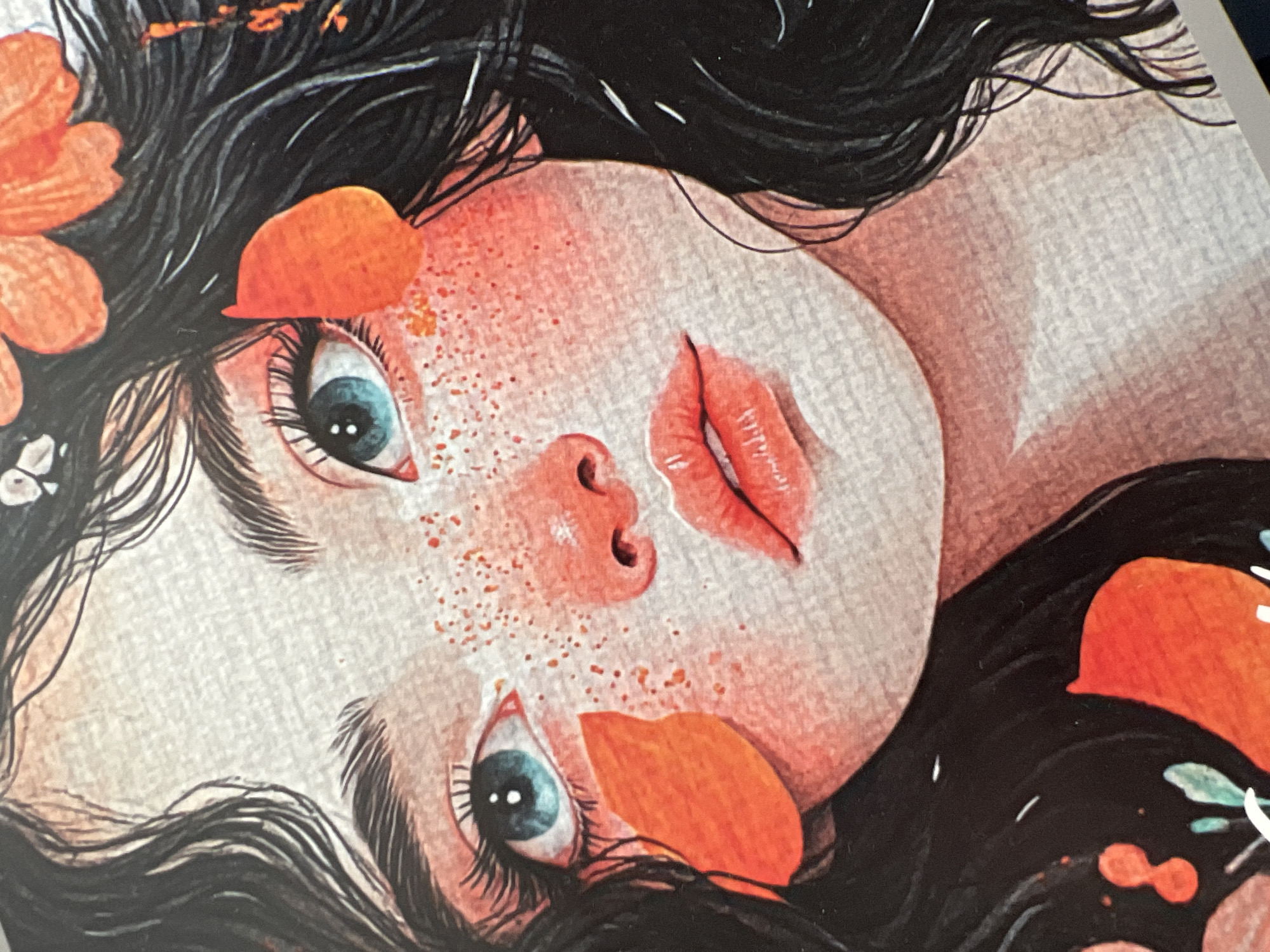 This is a close-up, artistic rendering of a young person's face, depicted in a style that blends illustration and painting. The subject has striking blue eyes with dark lashes and appears to be looking upwards. Their skin is rendered with a soft, peachy tone, dotted with delicate orange freckles. The lips are full and painted a vibrant coral.
The person's dark, wavy hair frames their face, and several bright orange petal-like shapes are scattered around their head, suggesting a floral or natural theme. One petal rests near their left eye, and another near their right cheek. The background is a textured off-white, contributing to the illustrative feel.
The overall impression is one of gentle introspection or dreamy repose. The lighting is soft and diffused, not indicating a specific time of day. There are no visible text elements, and no clear environmental cues to suggest a specific location beyond the generalized natural elements. The artwork is cropped tightly, focusing entirely on the face and immediate surroundings, implying it may be part of a larger piece or a portrait.